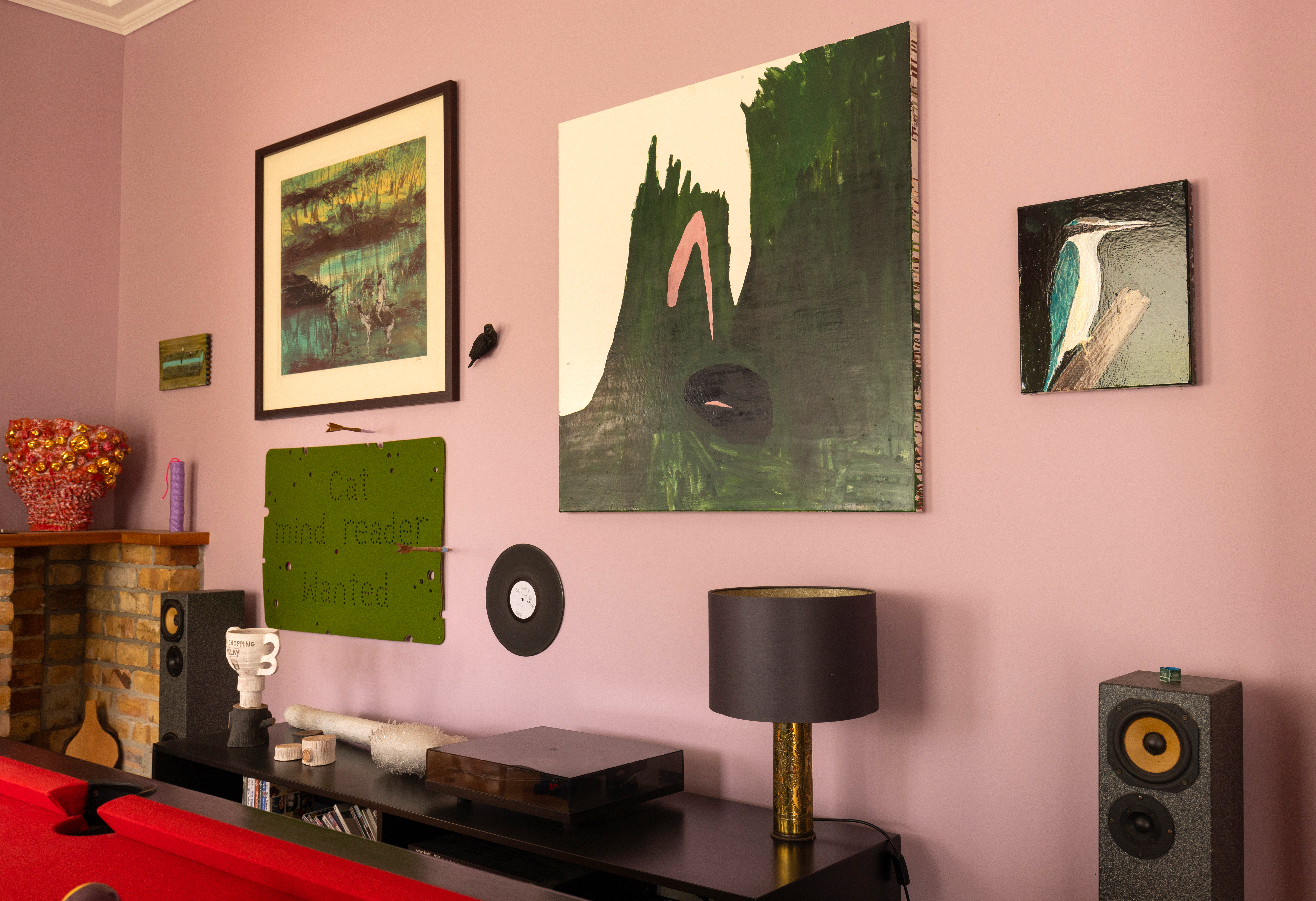 A fan of mixing up mediums, this living room features a ceramic vessel by Virginia Leonard, a sculpture by Iain Cheesman, paintings by Peter Cleverley and Richard Lewer, a print by Sydney Nolan, a felt artwork by Iain Cheesman, and a carved timber 'record' sculpture by Glen Hayward; on the cabinet, a ceramic Sculpture by Mike Petre and a glass sculpture by Vicki Fanning. Photo / Ginny Fisher