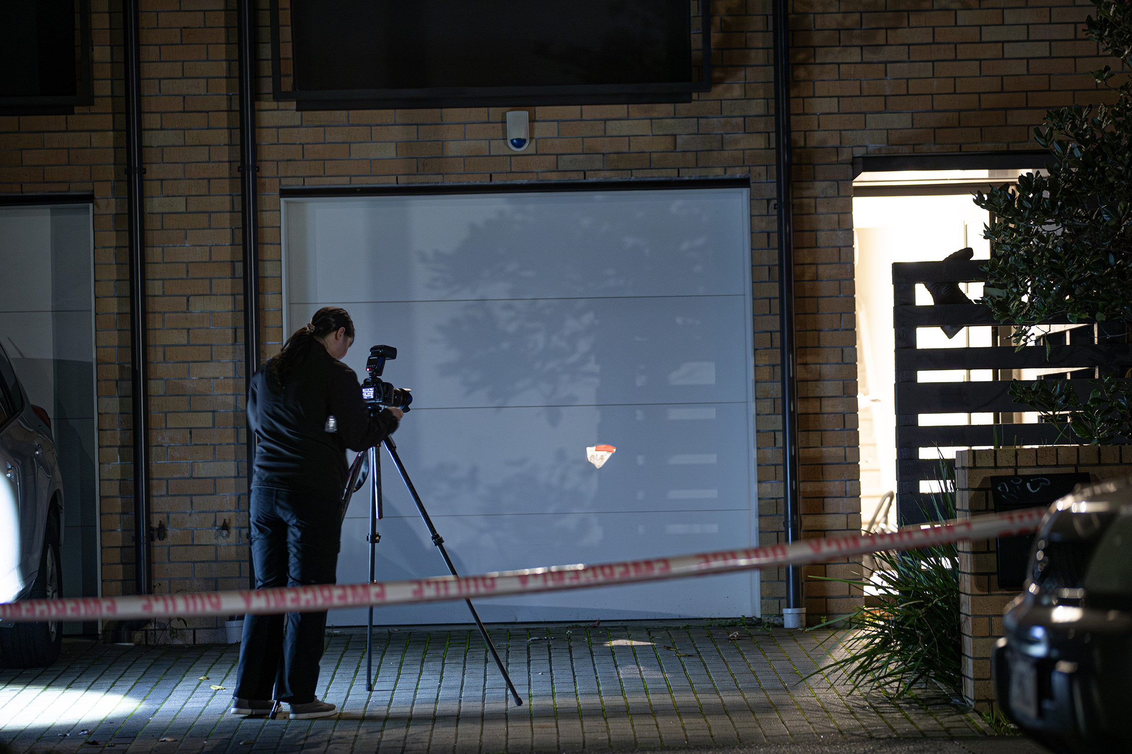A police officer at the scene on Ahuwhenua Crescent in Onehunga after a shot was fired through the garage door last night, hitting a vehicle. Photo / Hayden Woodward