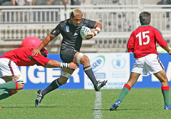 Stand-in All Blacks captain Jerry Collins strides through a Portuguese defender during their 2007 Rugby World Cup match in Lyon. Photo / Brett Phibbs