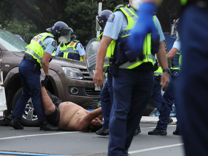 A shirtless man is dragged by police. Photo / Mike Scott
