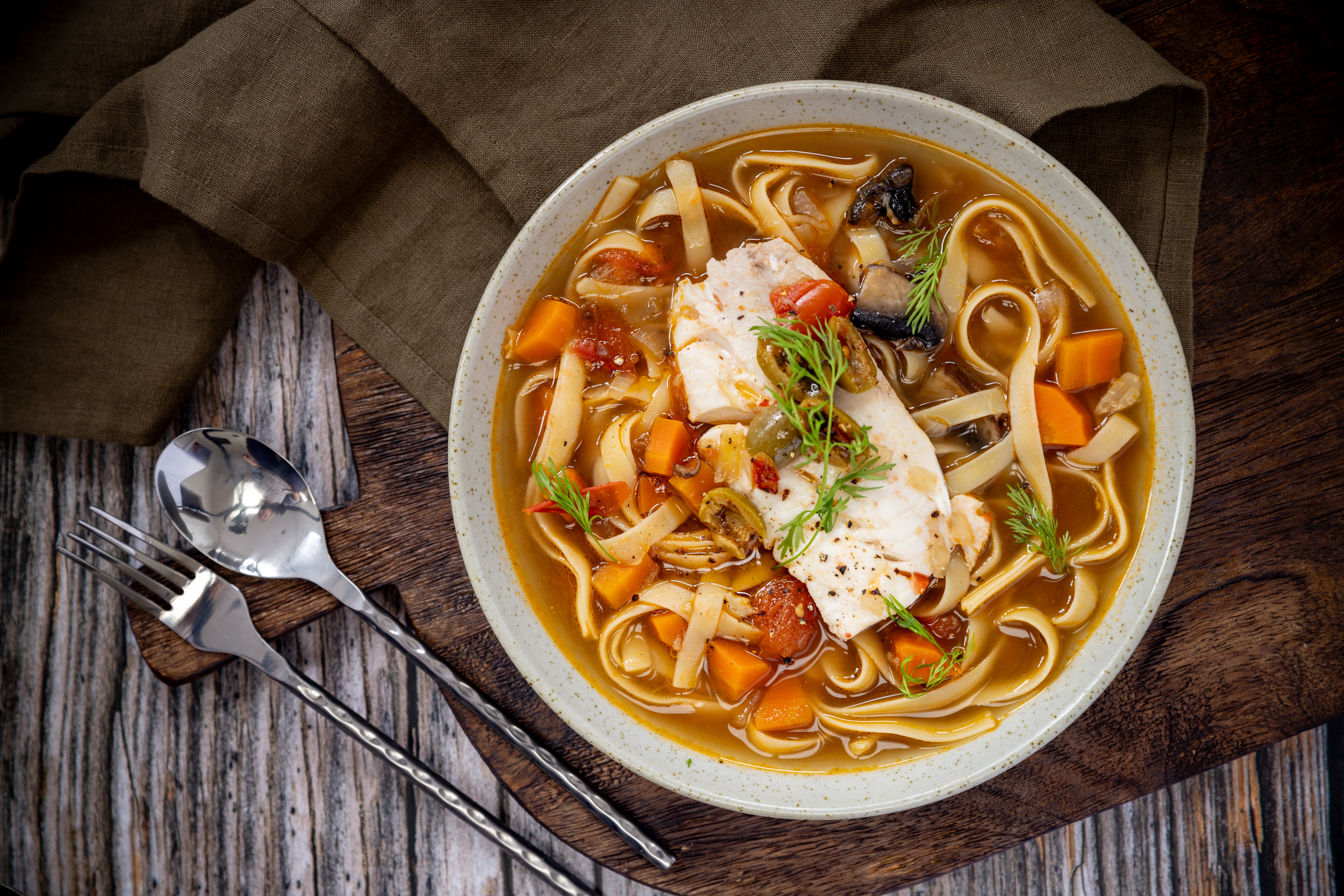 This golden dish combines poached white fish with fettuccine, olives and aromatic Tuscan herbs. Photo / Babiche Martens