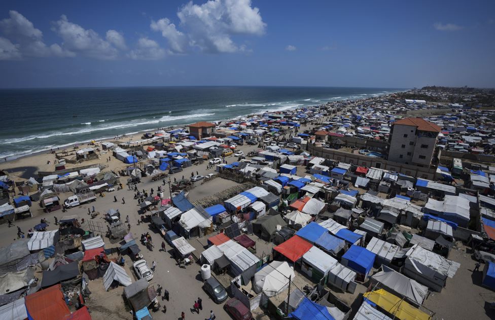 Palestinians displaced by the Israeli air and ground offensive on the Gaza Strip walk through a makeshift tent camp in Deir al Balah, Gaza. Photo / AP