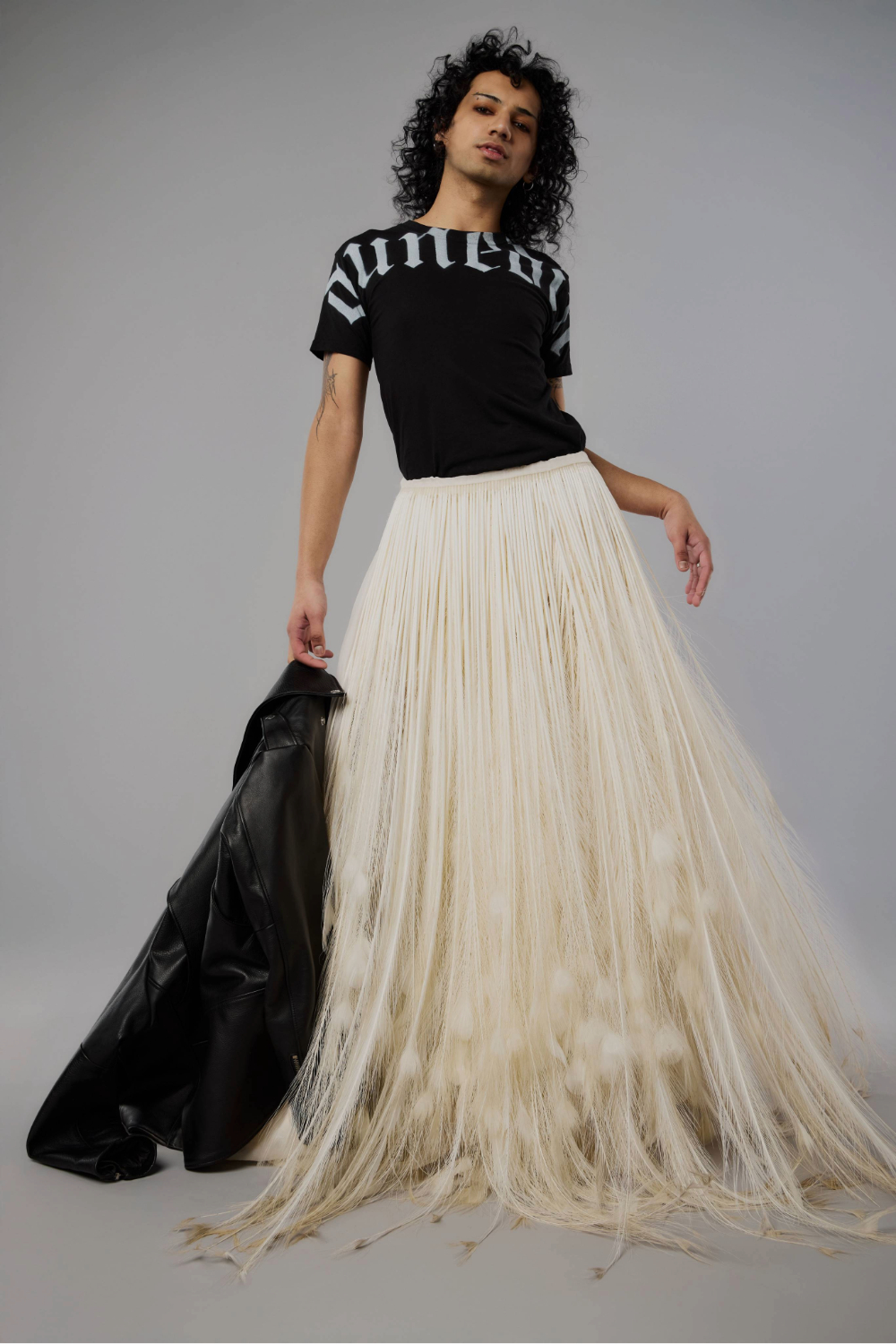 Adam Banoori wears a Nom*D T-shirt, Stolen Girlfriends Club leather jacket and a custom feather skirt by Poneke based designer Austin Delaney Girdlestone. Photo / Mara Sommer for New Zealand Fashion Week.