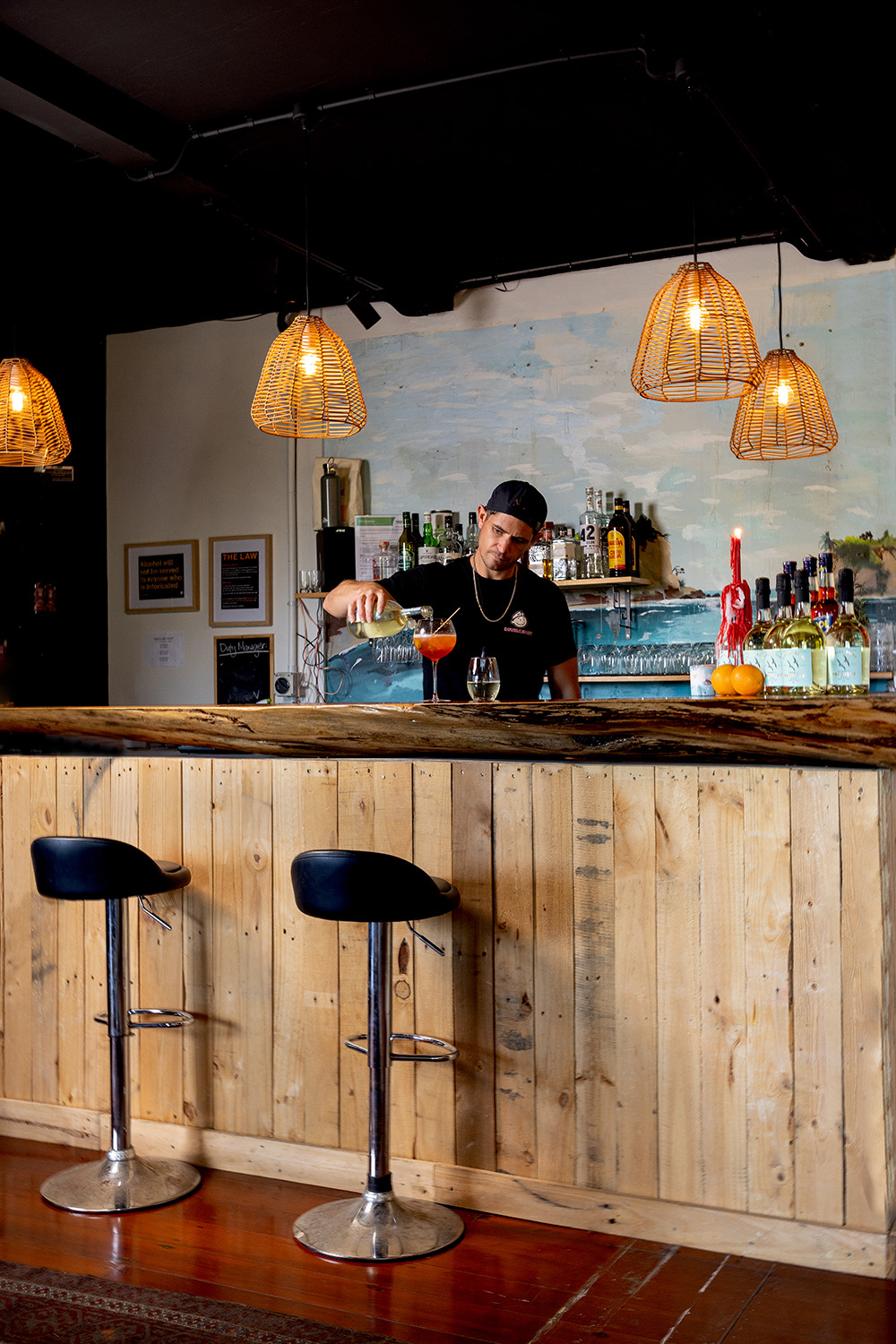 The youngest Steel brother, Bryce, tends the newly opened bar in the historic Muriwai Lodge. Photo / Babiche Martens