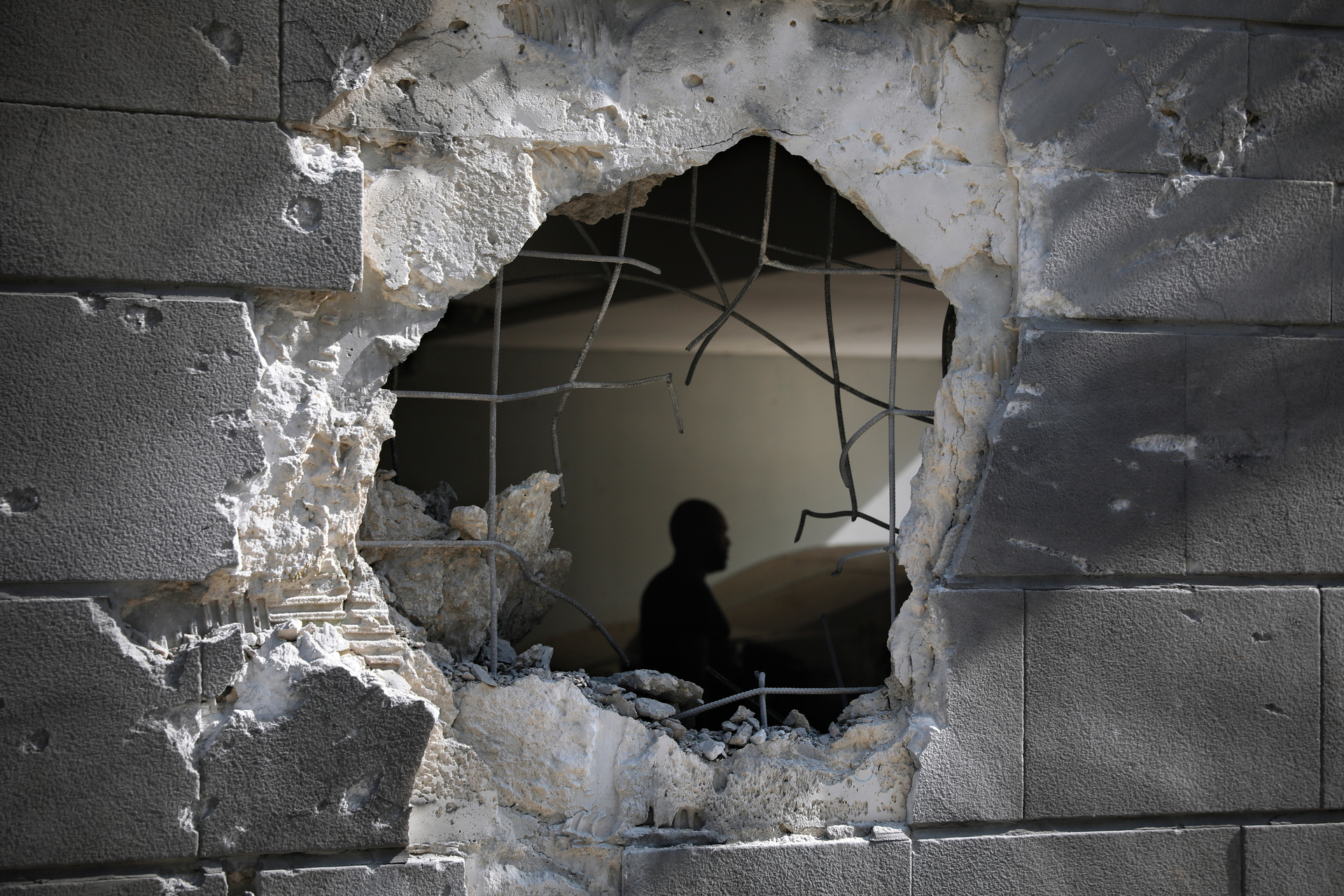 A man is seen trough a hole in a wall of a residential building after it was struck by a rocket fired from the Gaza Strip in Ashkelon, Israel. Photo / AP