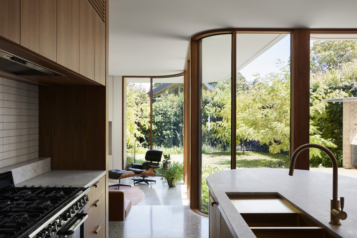 An elegant, sinuous glass wall blurs the boundary between the interior and the lush garden outside. Photo / Tess Kelly