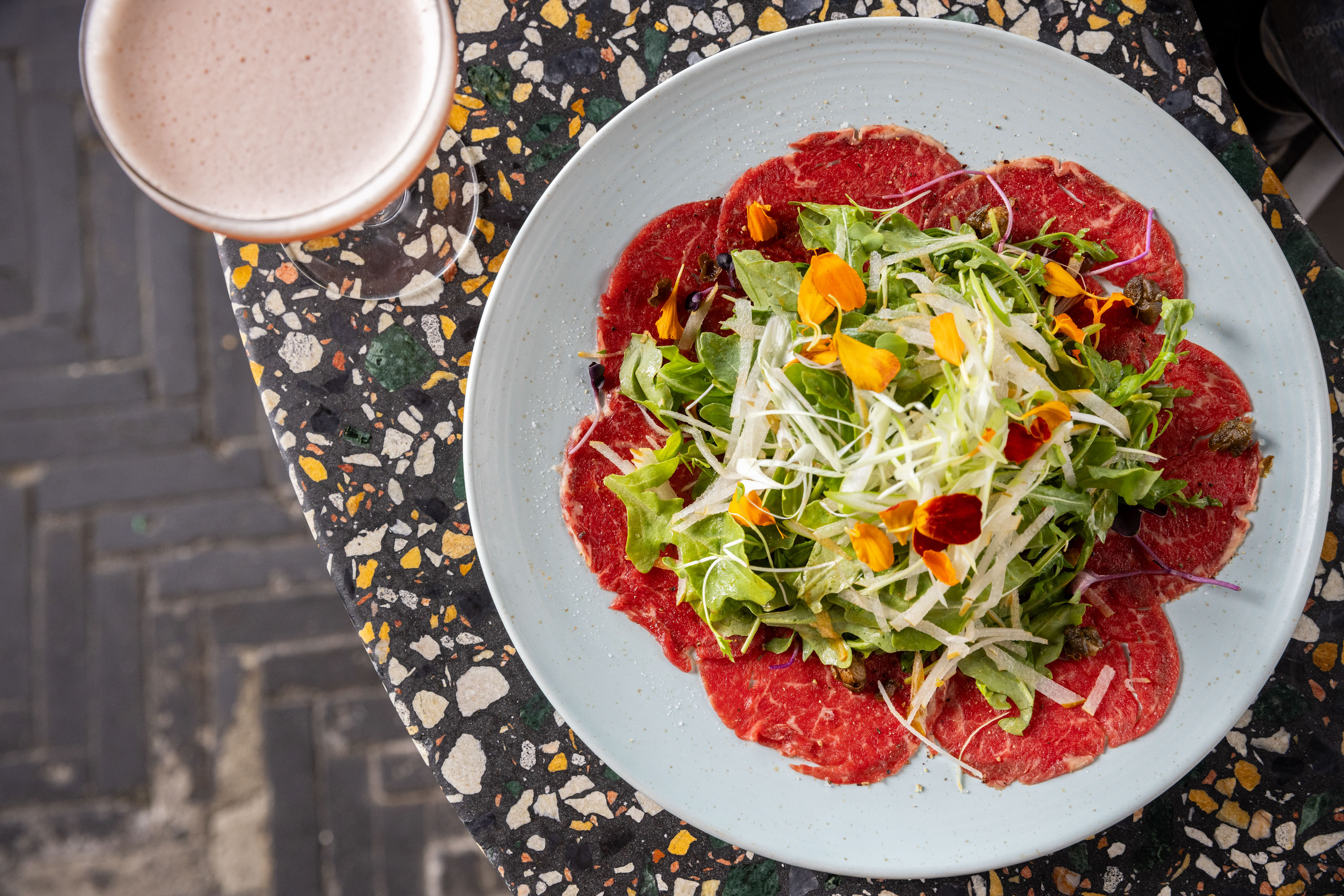 Beef carpaccio with lightly dressed rocket and pear salad. Photo / Babiche Martens