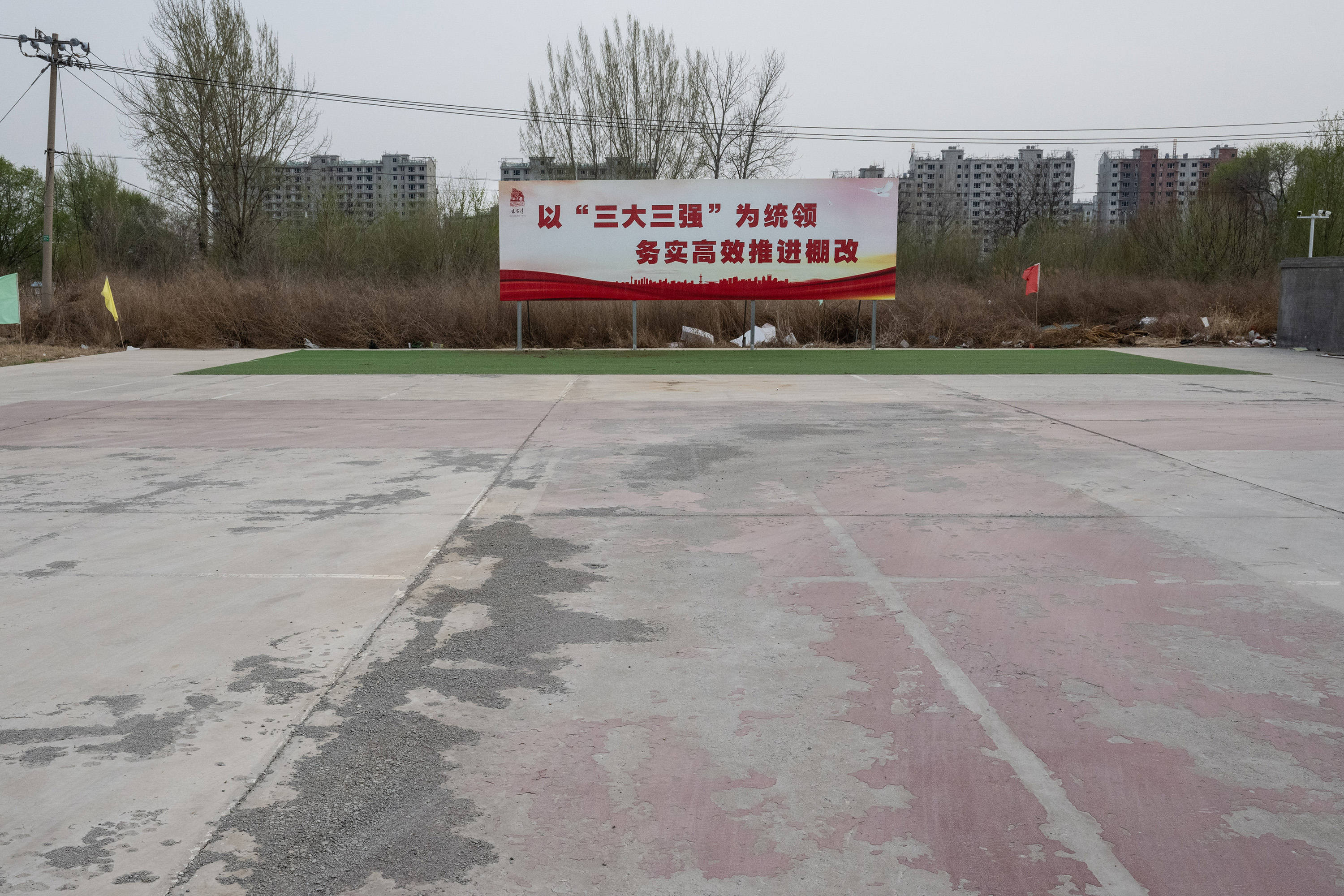 A site of a demolished village in Zhangjiawan features a billboard with official slogans promoting the renovation of “shantytowns.” Photo / Gilles Sabrié, The New York Times
