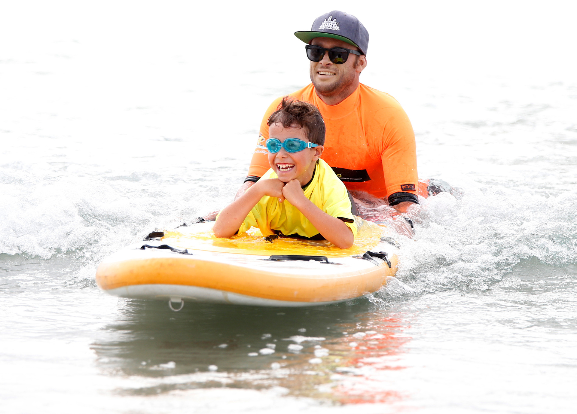 Kiarn Cherrington, 8, from One Tree Point surfs a wave with volunteer and surf instructor Simon Egginton from Tutukaka.
