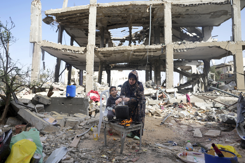 Palestinian woman Hiyam Qudih cooks in front of her family's building destroyed in the Israeli bombardment of the Gaza Strip in the village of Khuza'a. Photo / AP Adel Hana)
