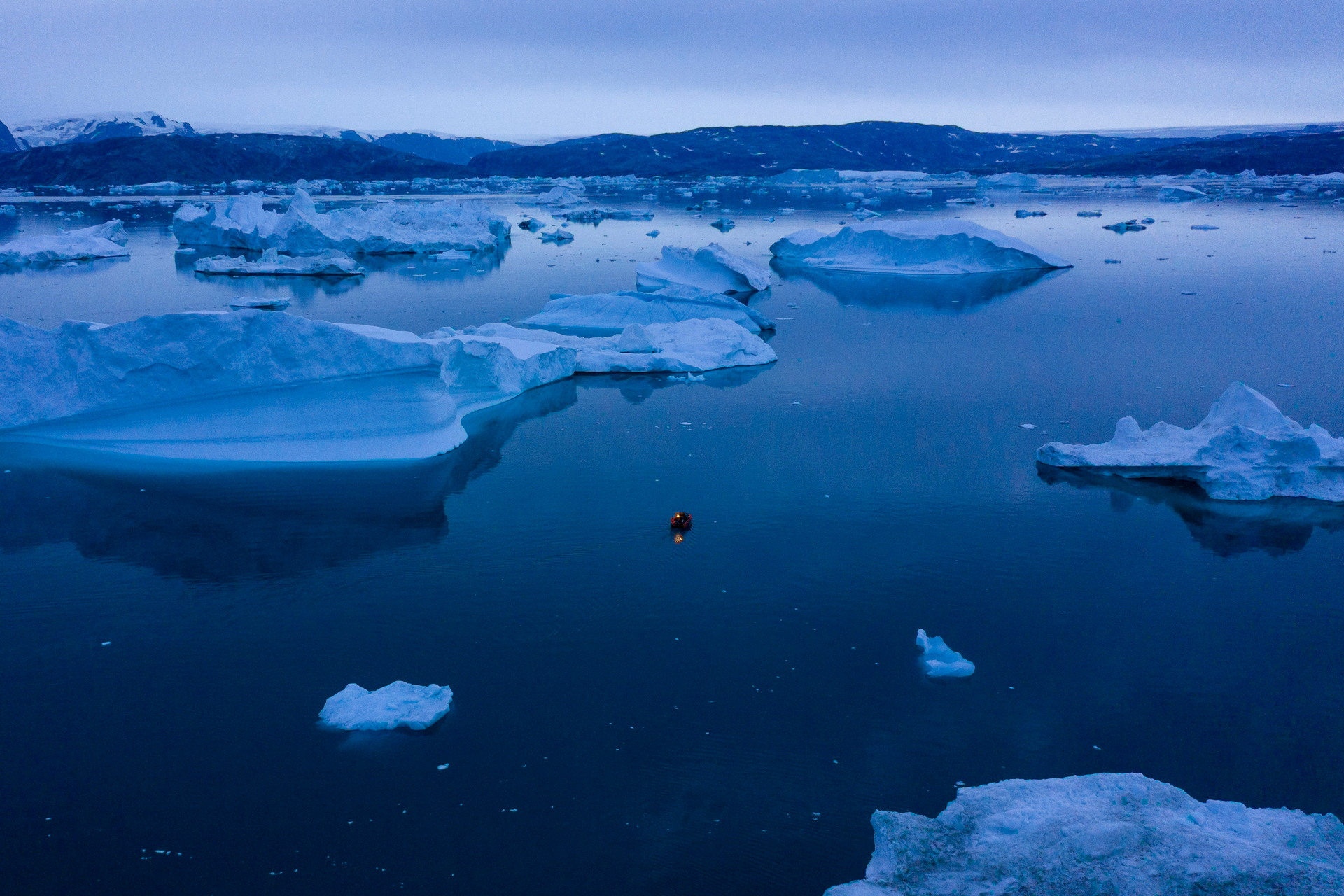 A boat navigates at night between icebergs in eastern Greenland. Photo / AP