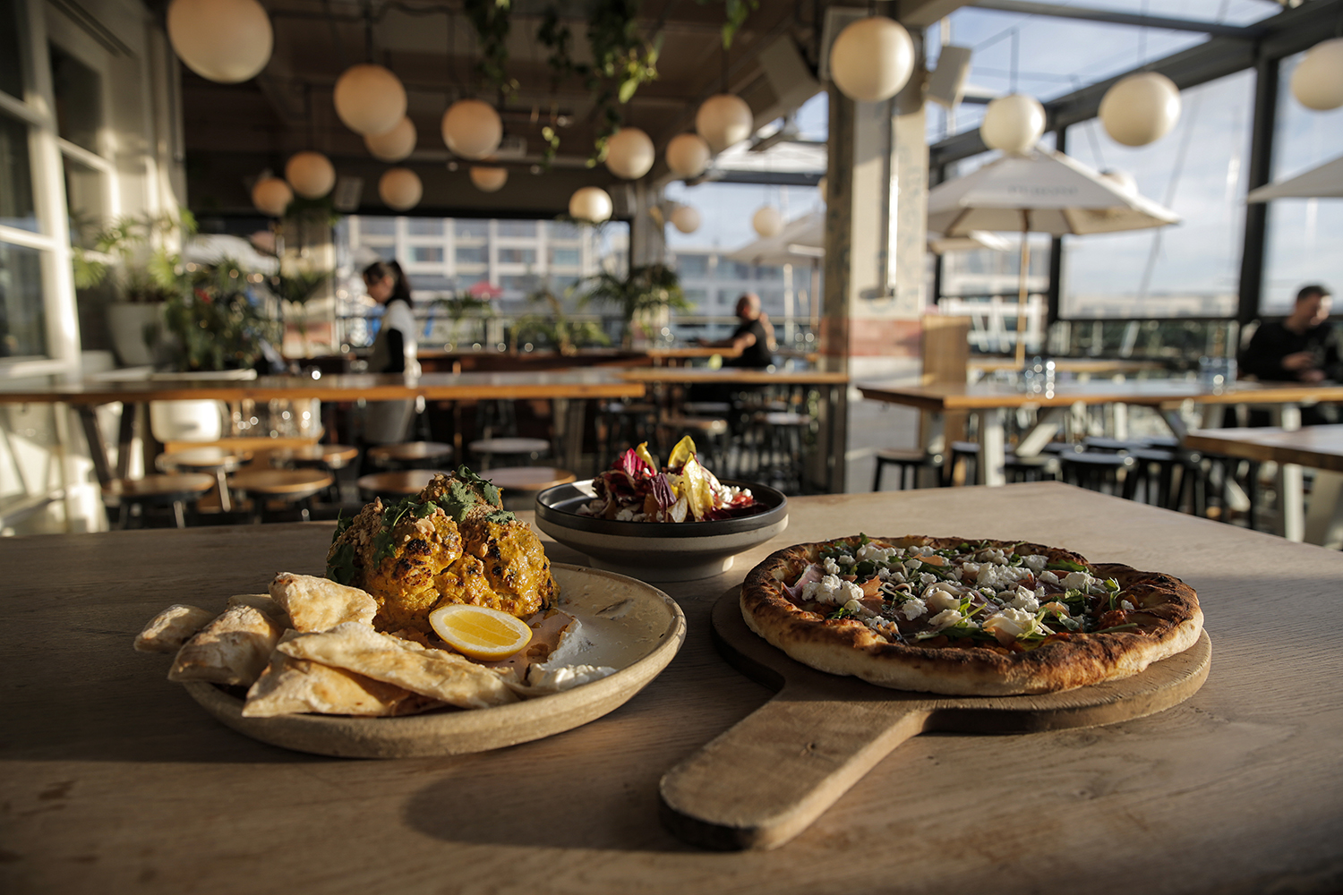 Prosciutto and butternut pizza, cauliflower and the bitter leaf salad from the menu at Saint Alice. Photo / Alex Burton