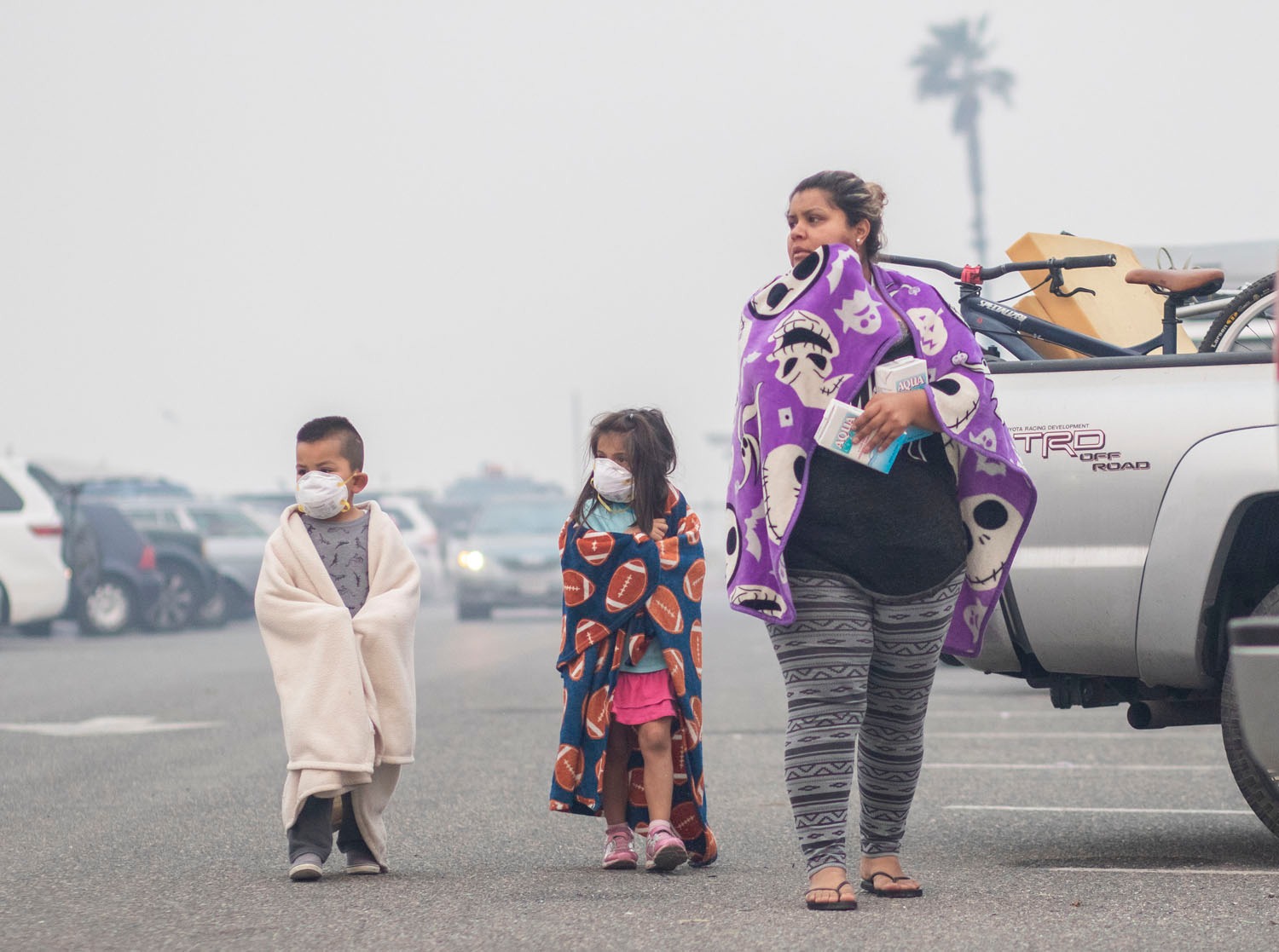 Albert Perez, 4, and his cousin Neveah Carbonati, 5, wear masks to help them breathe while with Yolanda Vela, Neveah's mother, after having slept in a car during evacuations. Photo / Washington Post