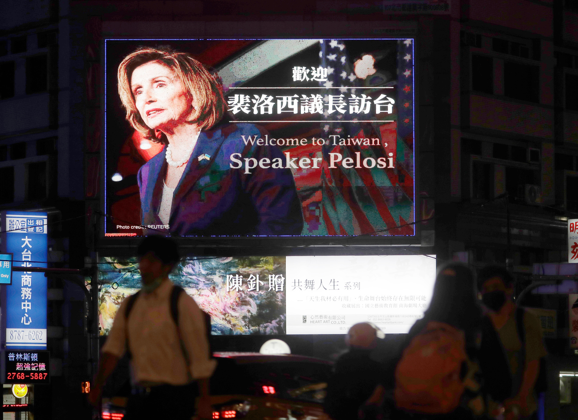 People in downtown Taipei walk past a billboard welcoming Pelosi. Photo / Chiang Ying-ying, AP