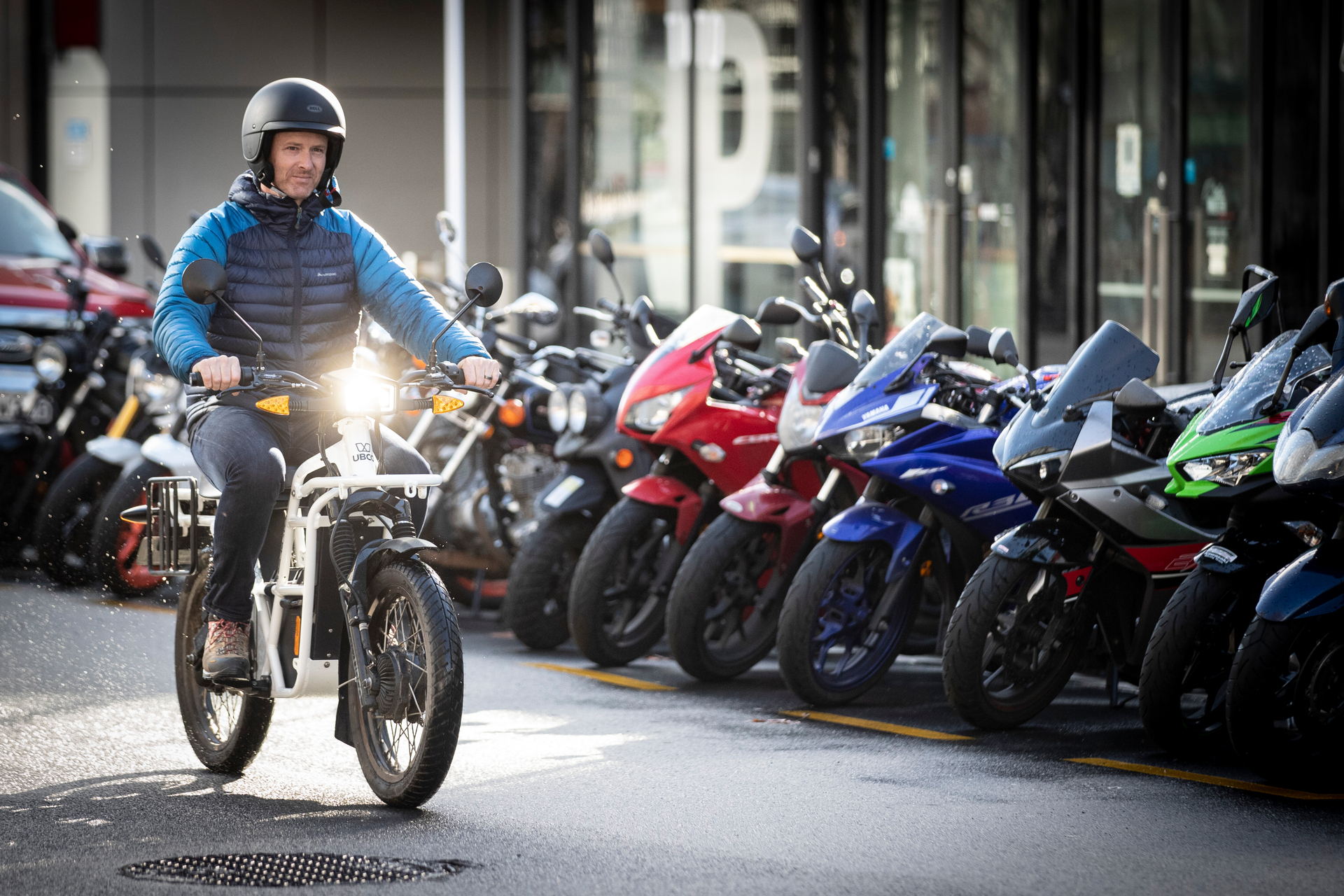 Silent running: Ubco CEO Timothy Allan rides an Ubco 2X2 ADV (short for Adventure Bike) past a lineup of more traditional motorcycles parked outside the NZ Herald's building. Photo / Jason Oxenham