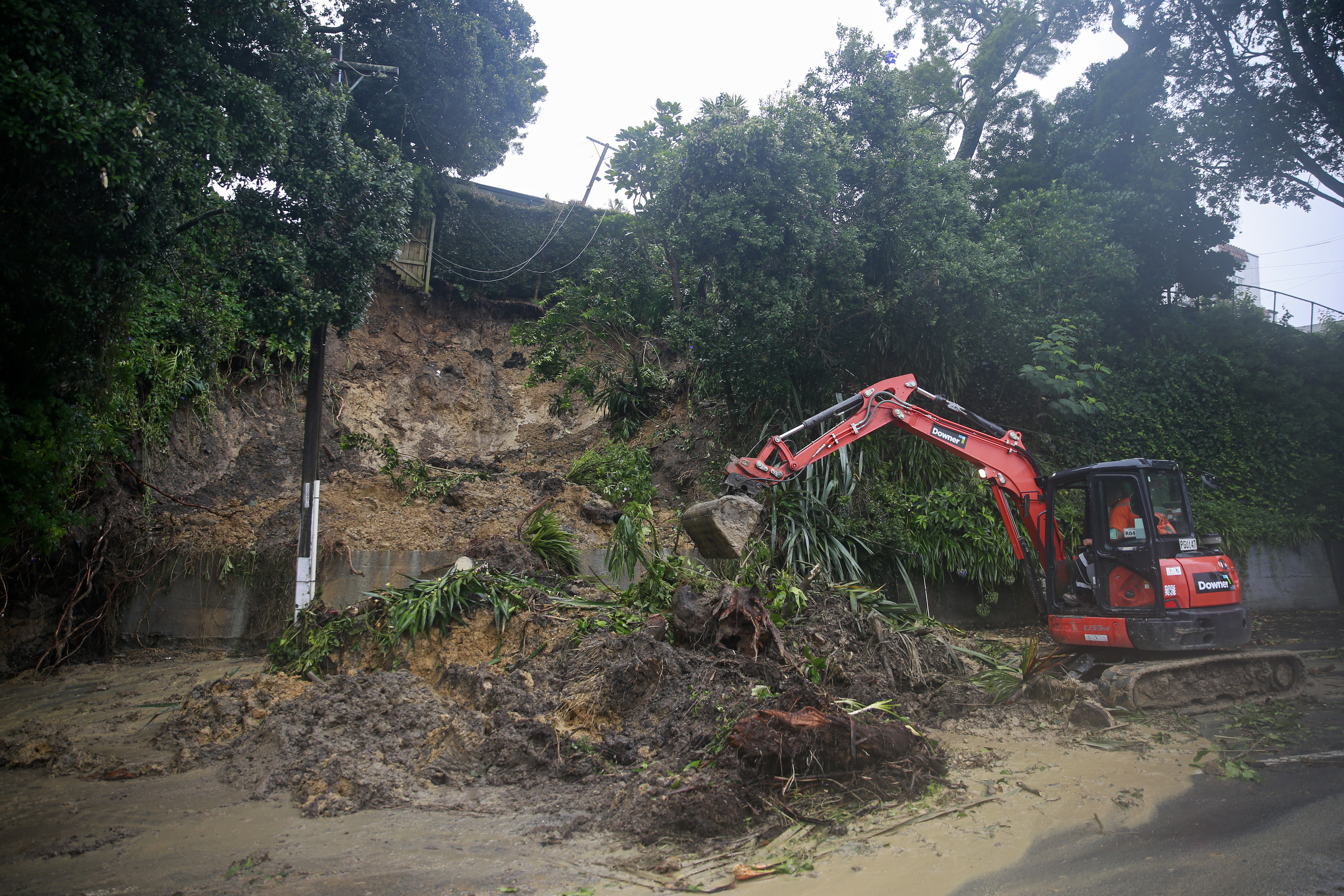 Workers clean up a slip after storms and flooding in Auckland. Photo / Alex Burton