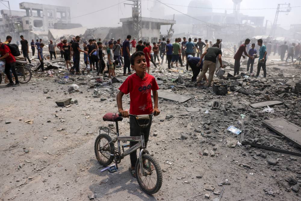 A young boy stands next to his bicycle as Palestinians check the devastation following an Israeli strike that hit Gaza City's southern al-Zeitoun neighbourhood. Photo / Bashar Taleb, AFP