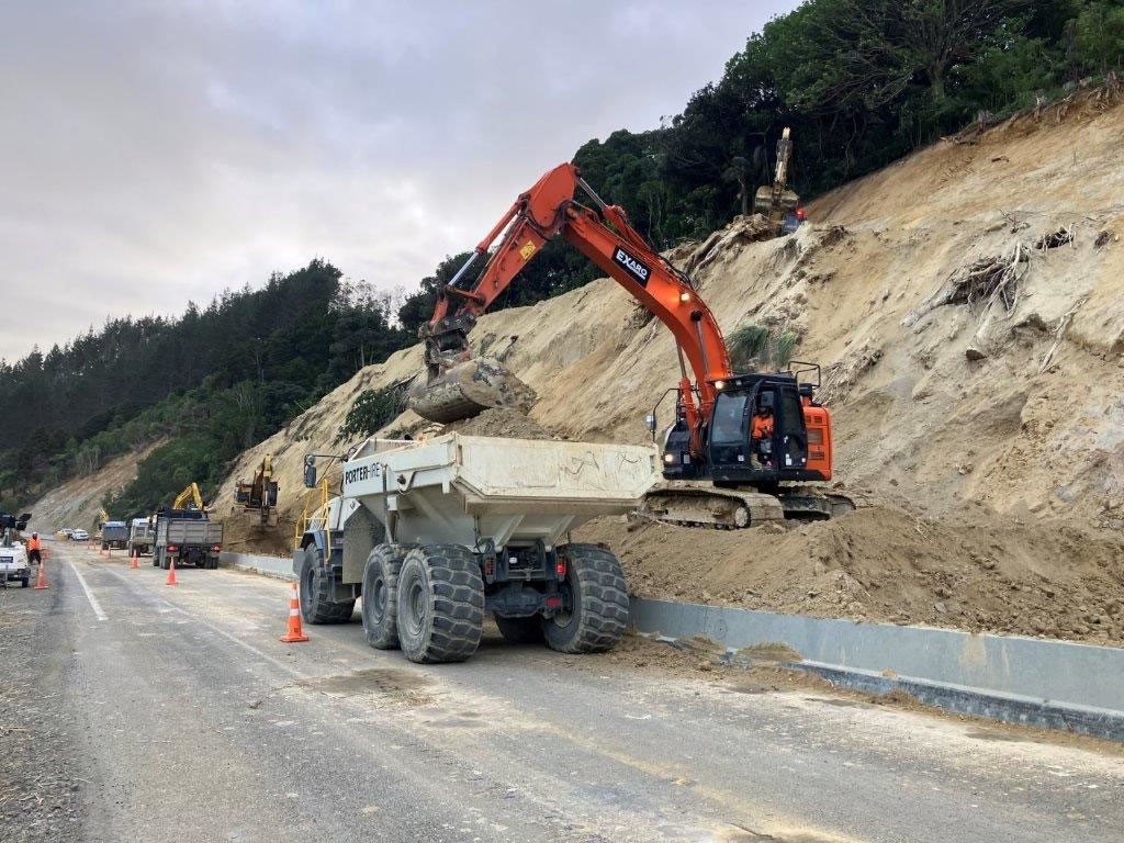 A digger moves some of the thousands of tonnes of dirt that has blocked SH1 over the Brynderwyns for months. Photo / File