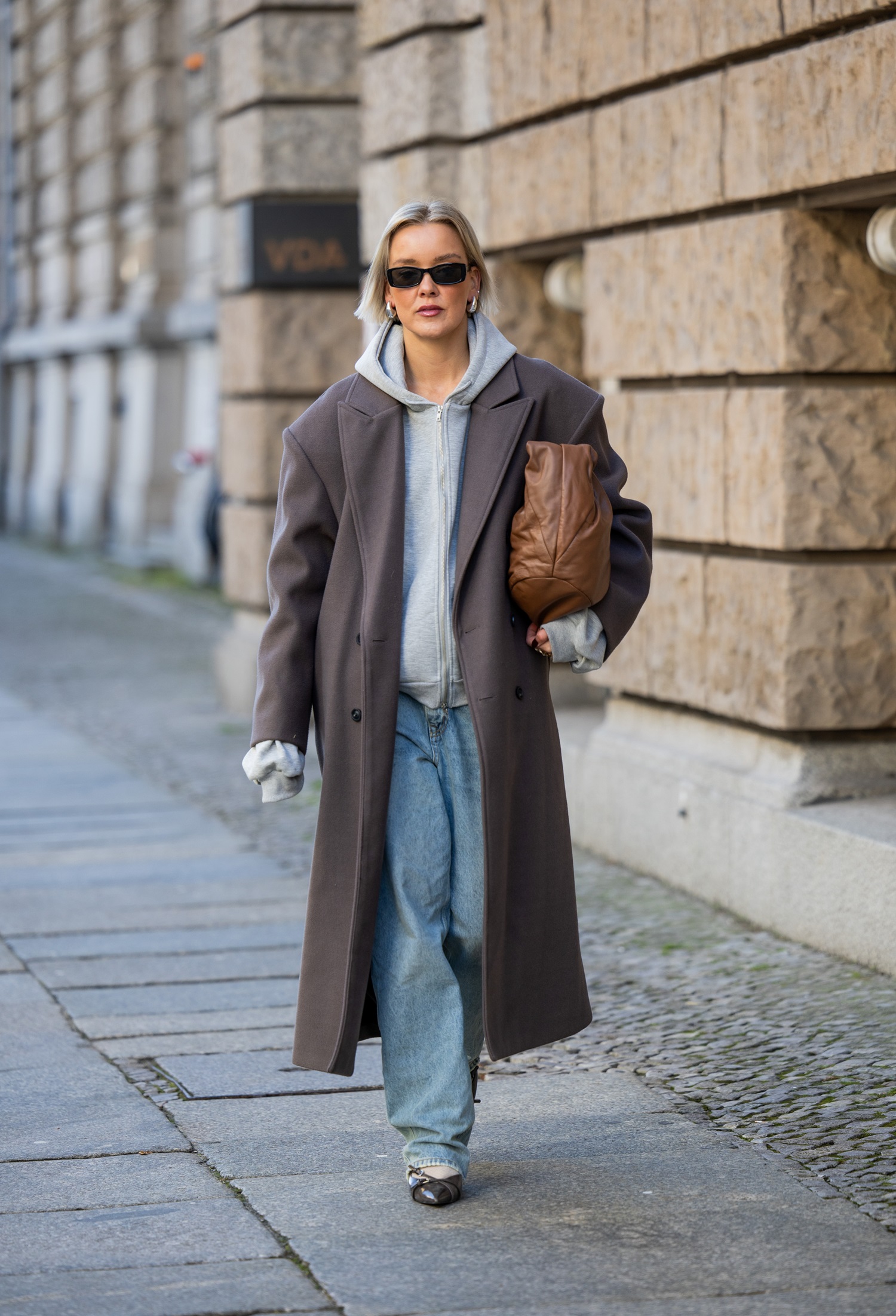 Fashion influencer Tina Haase styles a grey hoodie with a winter coat, jeans and oversized bag in Berlin. Photo / Getty Images