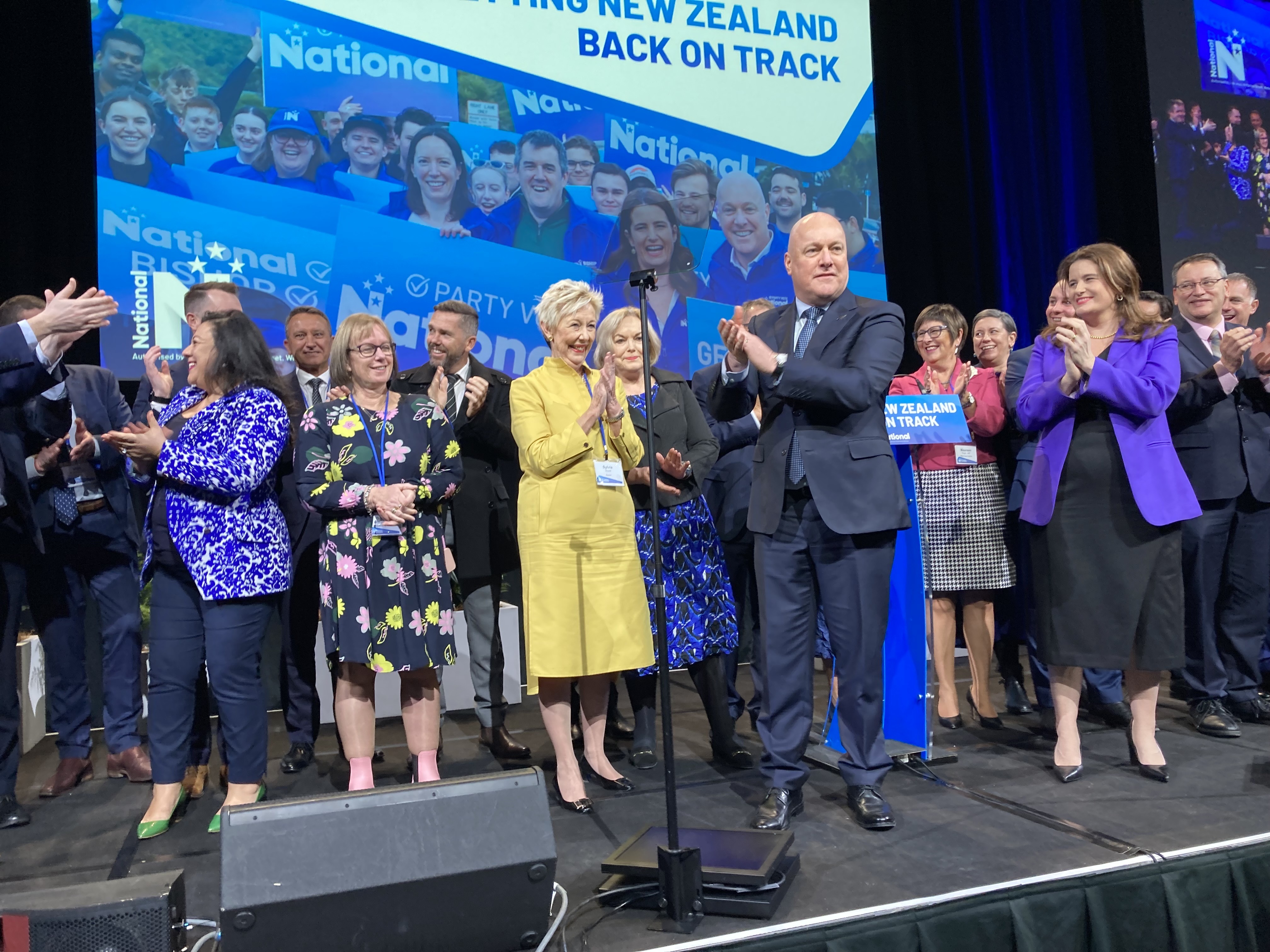 National Party leader Prime Minister Christopher Luxon, National Party president Sylvia Wood (left) and deputy leader Nicola Willis with MPs at the party's 2024 annual conference at Due Drop Events Centre in Manukau. Photo / Claire Trevett