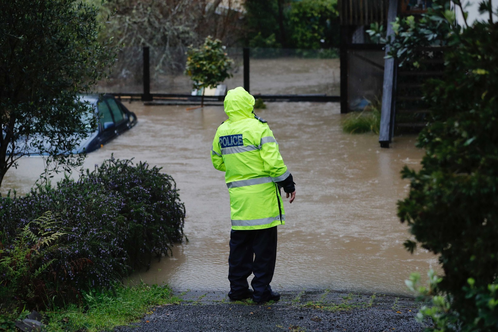 Car underwater and police checking on residents on Oraha Road, Kumeu. Photo / Dean Purcell