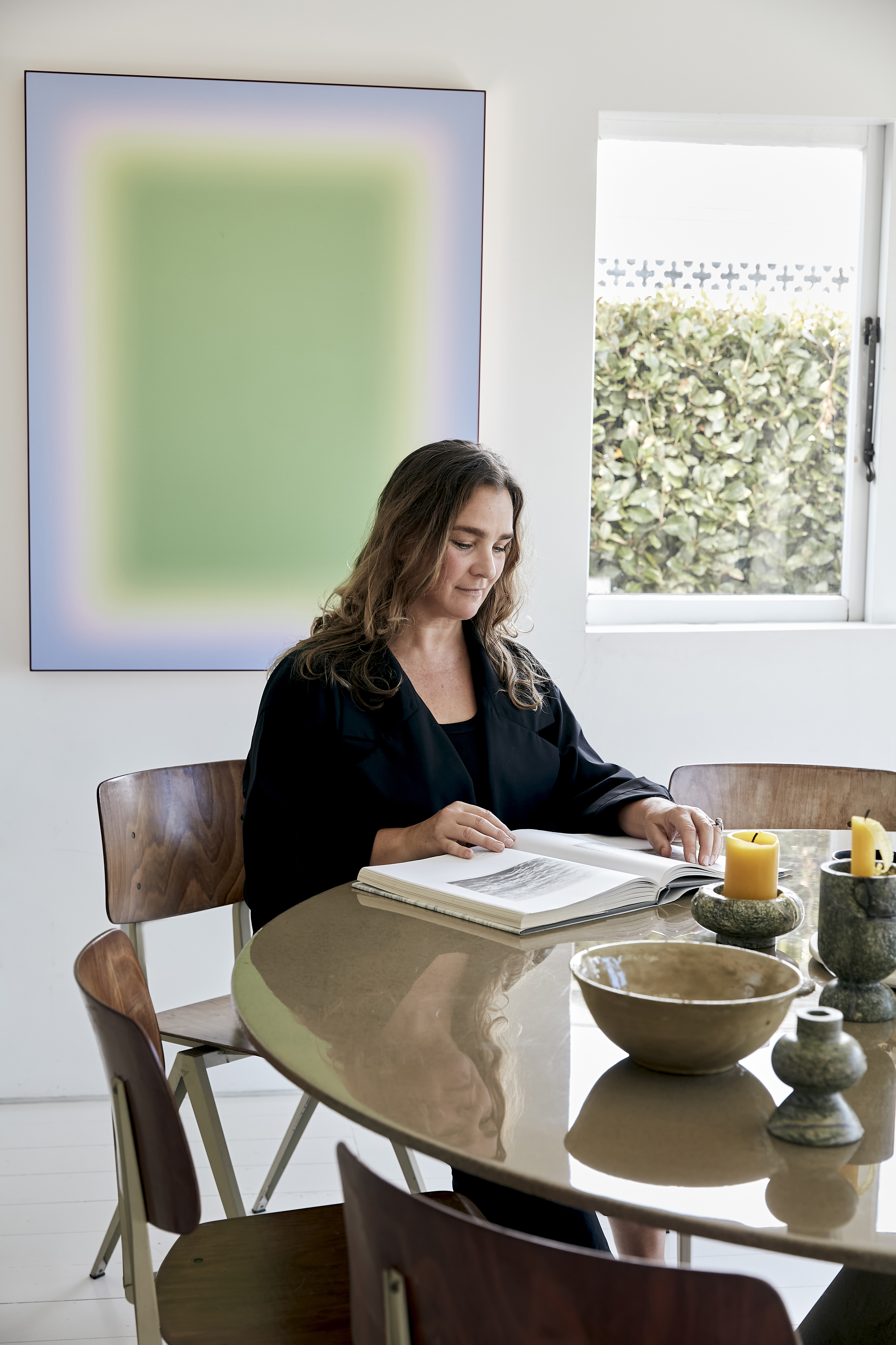 Sophie Fearon at home in her Freemans Bay kitchen in front of a painting by Jonny Niesche, vintage ceramic bowl from My Exhibition and vintage chairs from The Vitrine. Photo / Babiche Martens