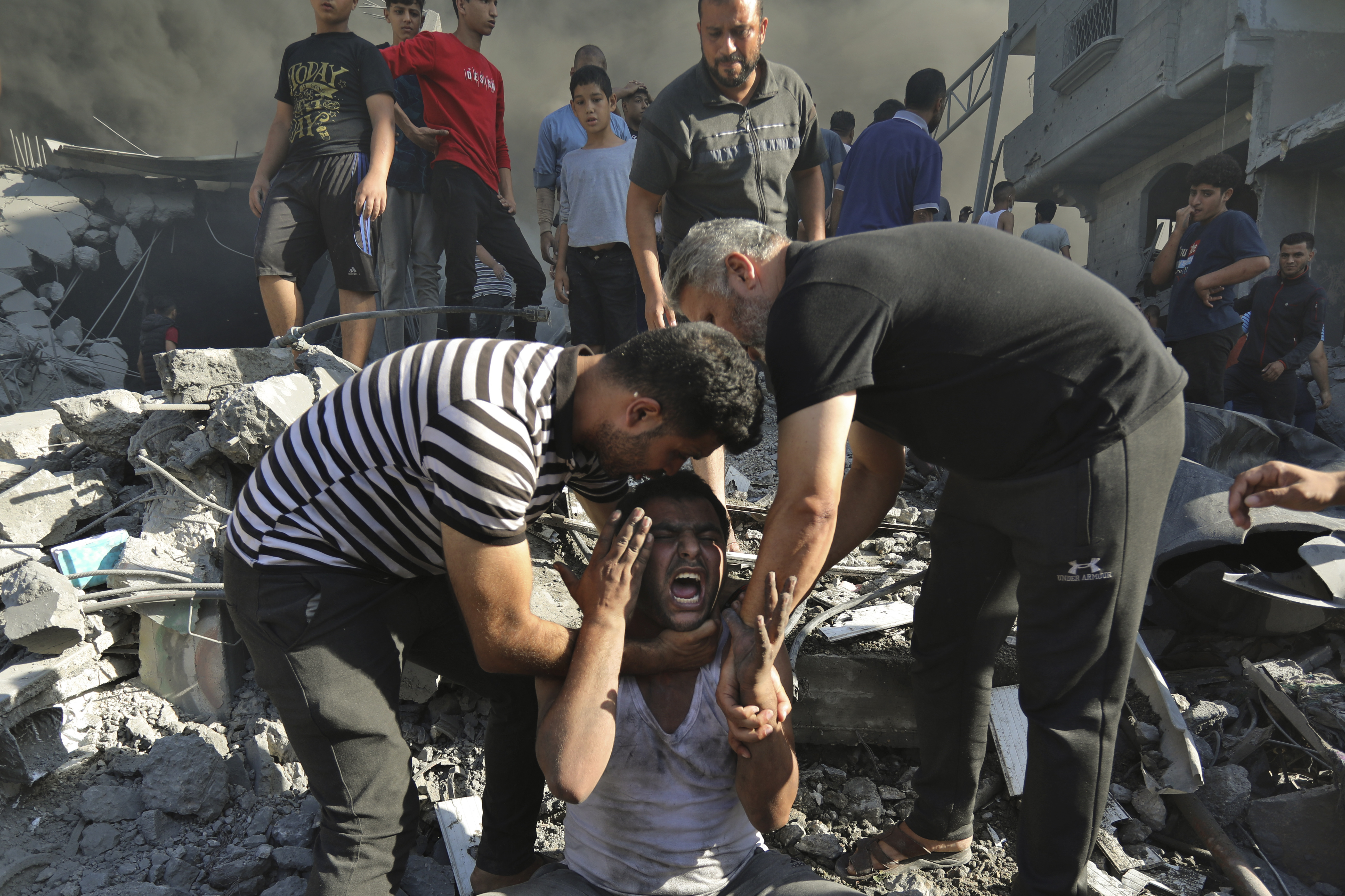 Palestinians comfort a crying man after losing relatives under the rubble of a destroyed house following an Israeli airstrike in Gaza City on Saturday. Photo / AP