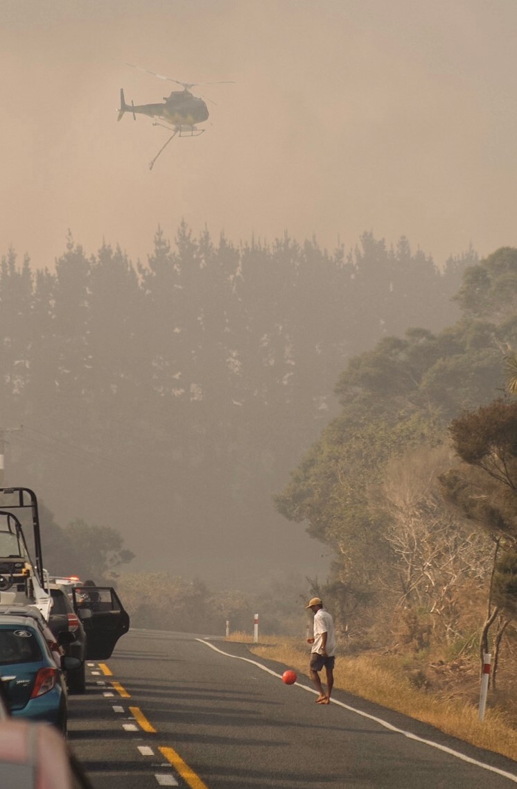A motorist passes the time with a ball during a State Highway 1 closure caused by the Kaimaumau fire's Boxing Day breakout. Photo / Jada Rolston