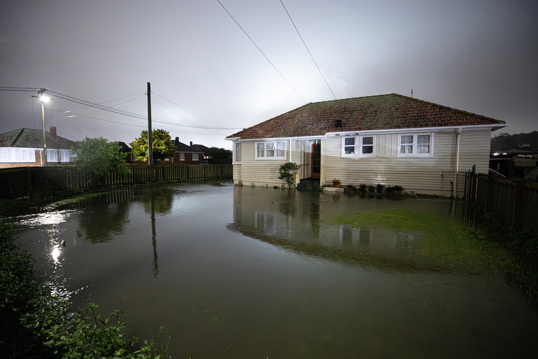 A home surrounded by floodwaters at the intersection of Potter and Parkinson Aves, Mt Roskill. Photo / Hayden Woodward