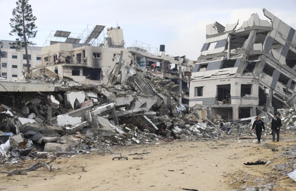 Palestinians walk past a building destroyed in the Israeli Bombardment of the Gaza Strip. Photo / AP