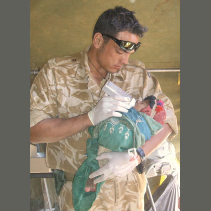 Lance Corporal Luke Tamatea feeds a baby in Afghanistan.