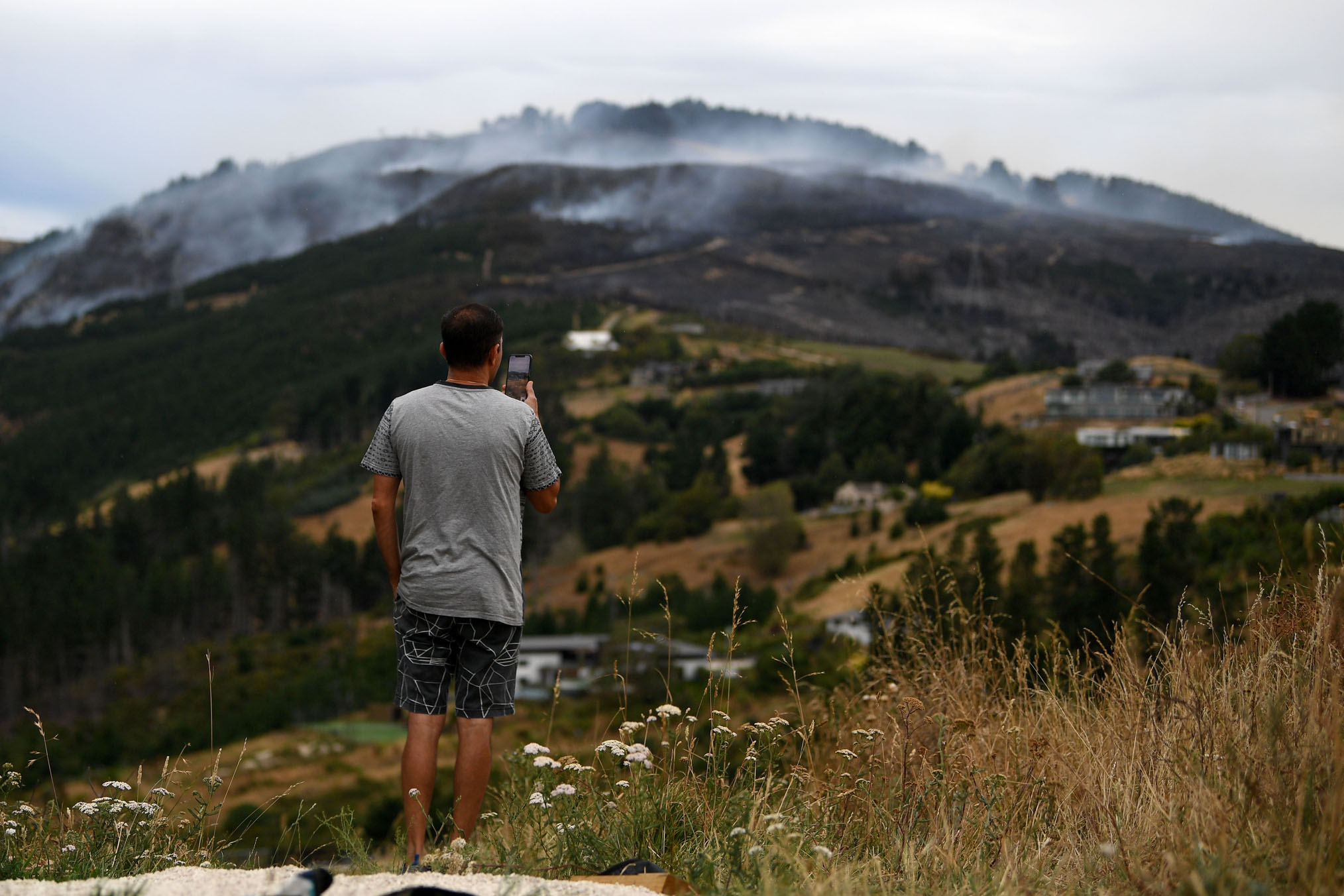 A member of the public films as the Port Hills fire burns away in the background. Photo / Joe Allison