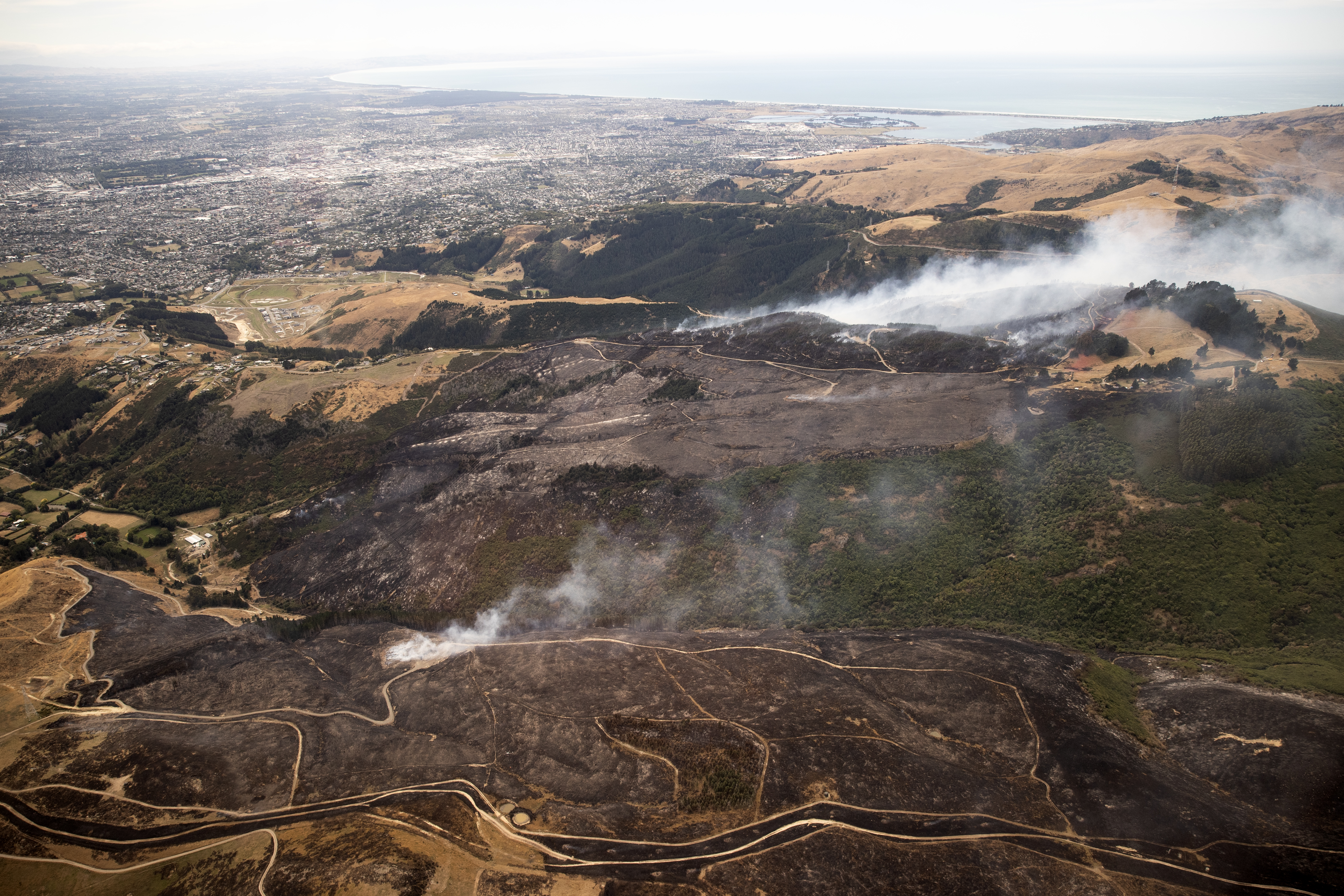 Christchurch can be seen in the distance as the fire continues to burn on Thursday. Photo / George Heard