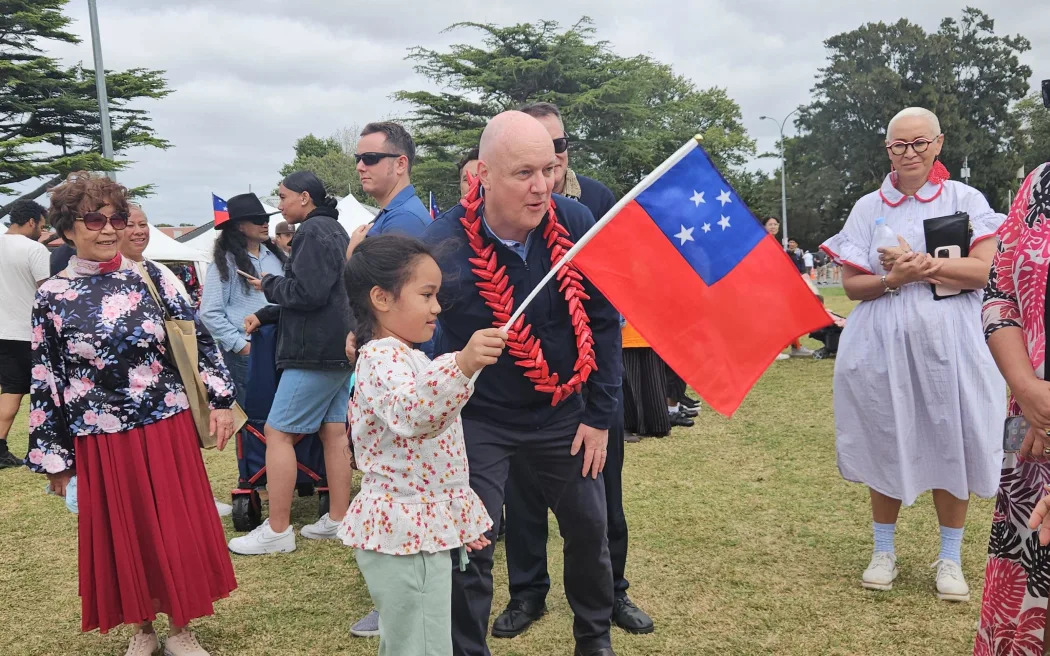 A girl shows her Samoan flag to Prime Minister Christopher Luxon. Photo / RNZ/Tiana Haxton