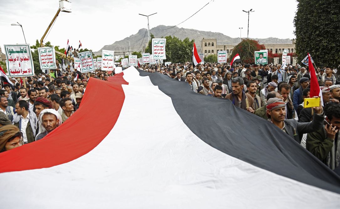 Houthi supporters chant slogans holding signs reading 