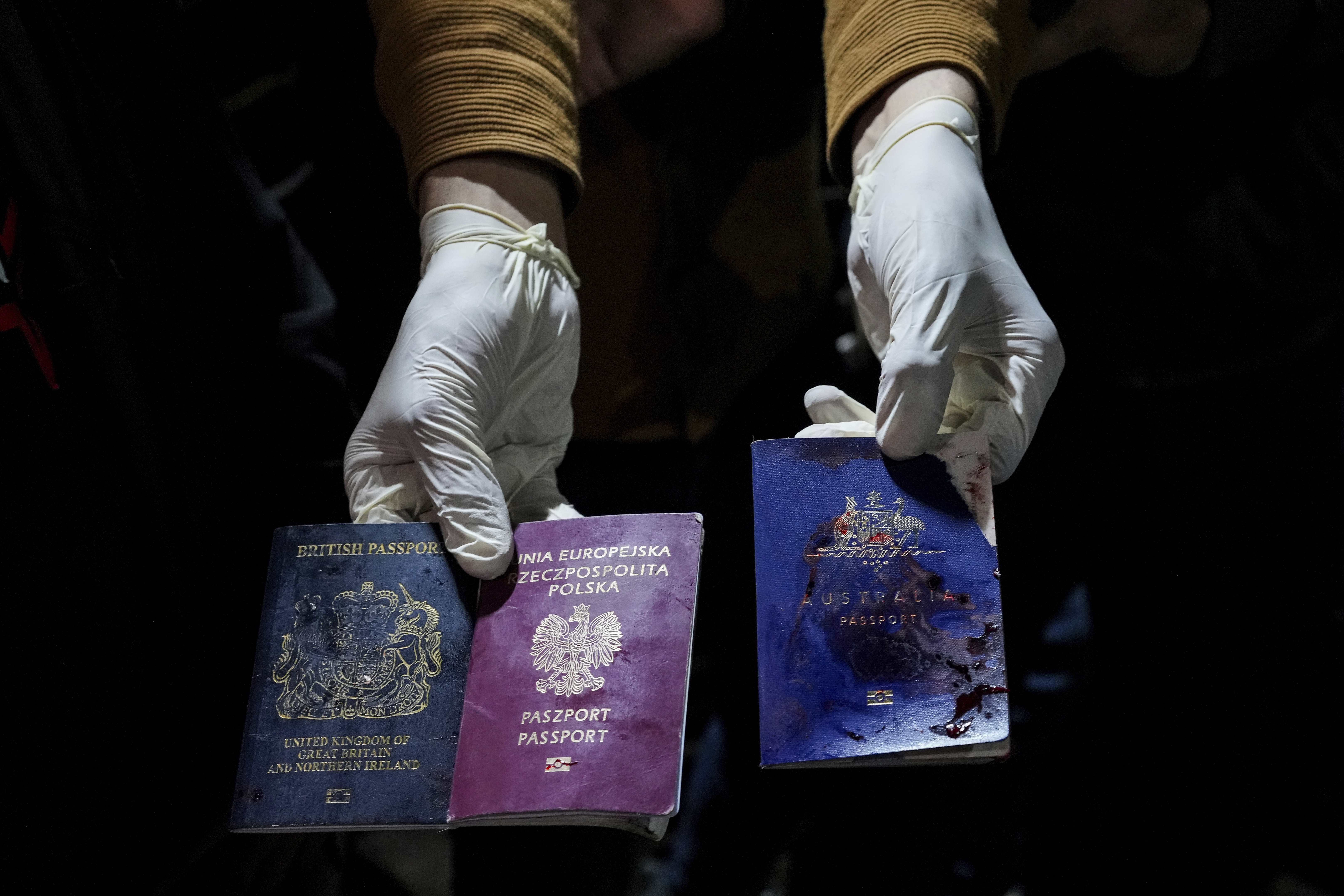 A man displays blood-stained British, Polish, and Australian passports after an Israeli airstrike, in Deir al-Balah, Gaza Strip. Photo / AP