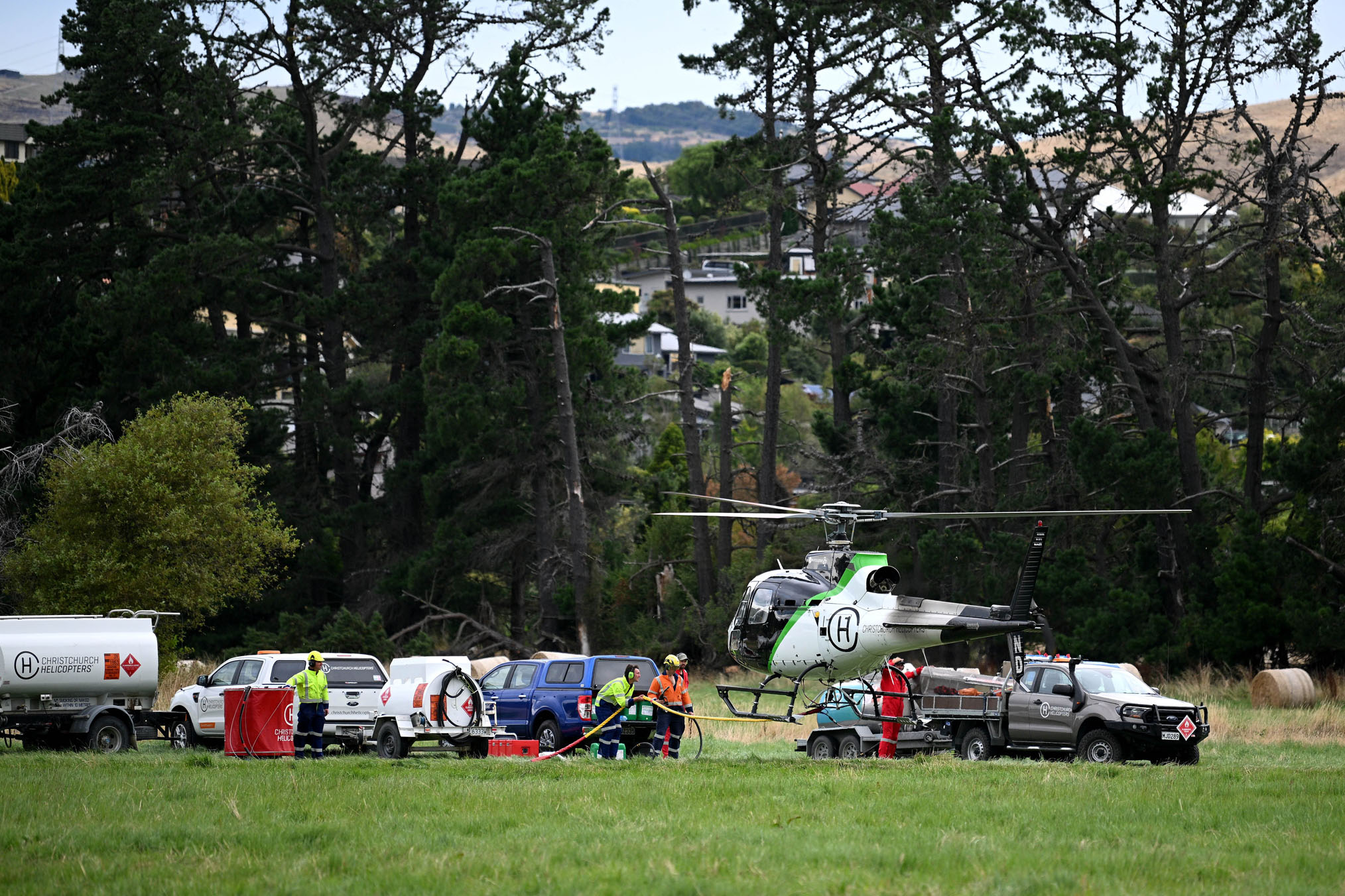 Helicopters prepare to carry out more flyovers - dropping buckets of water - on the fire. New Zealand Herald Photograph by Joe Allison