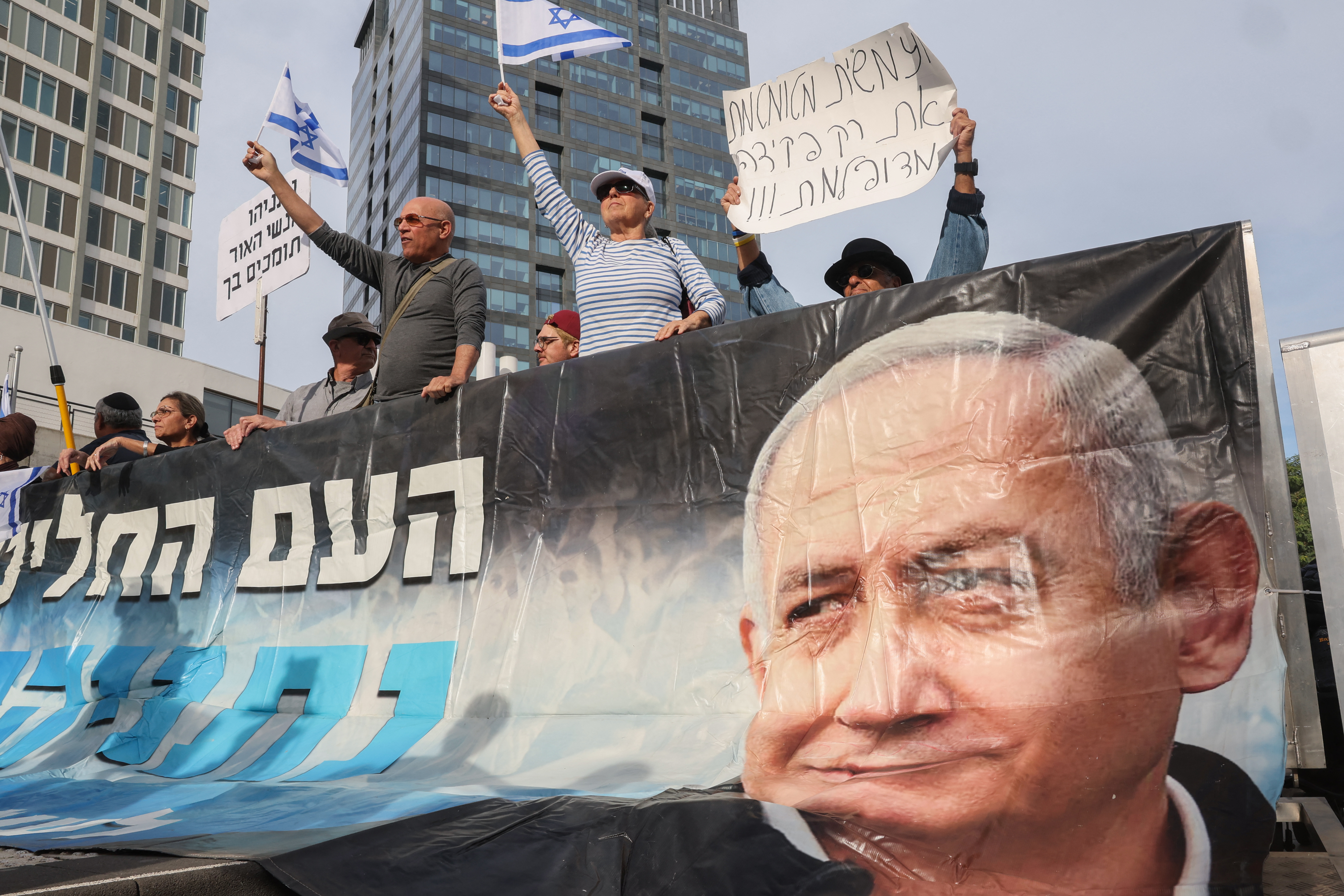 Demonstrators lift a banner and placards at a rally in support of Israel's Prime Minister Benjamin Netanyahu during his trial for corruption allegations at the District Court in Tel Aviv on December 10, 2024.Photo / AFP