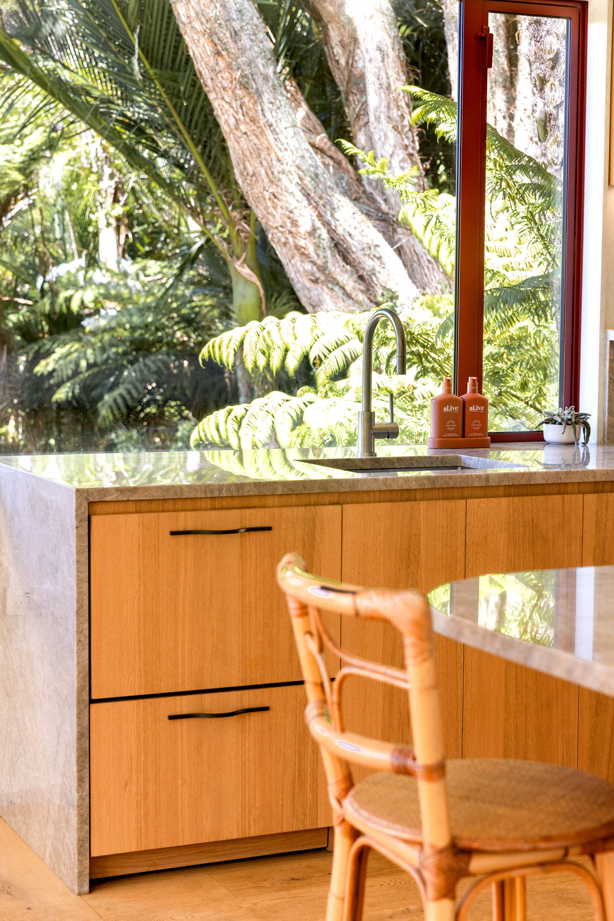 Pioneer Red joinery in the kitchen, which looks out to native bush. Photo / Babiche Martens