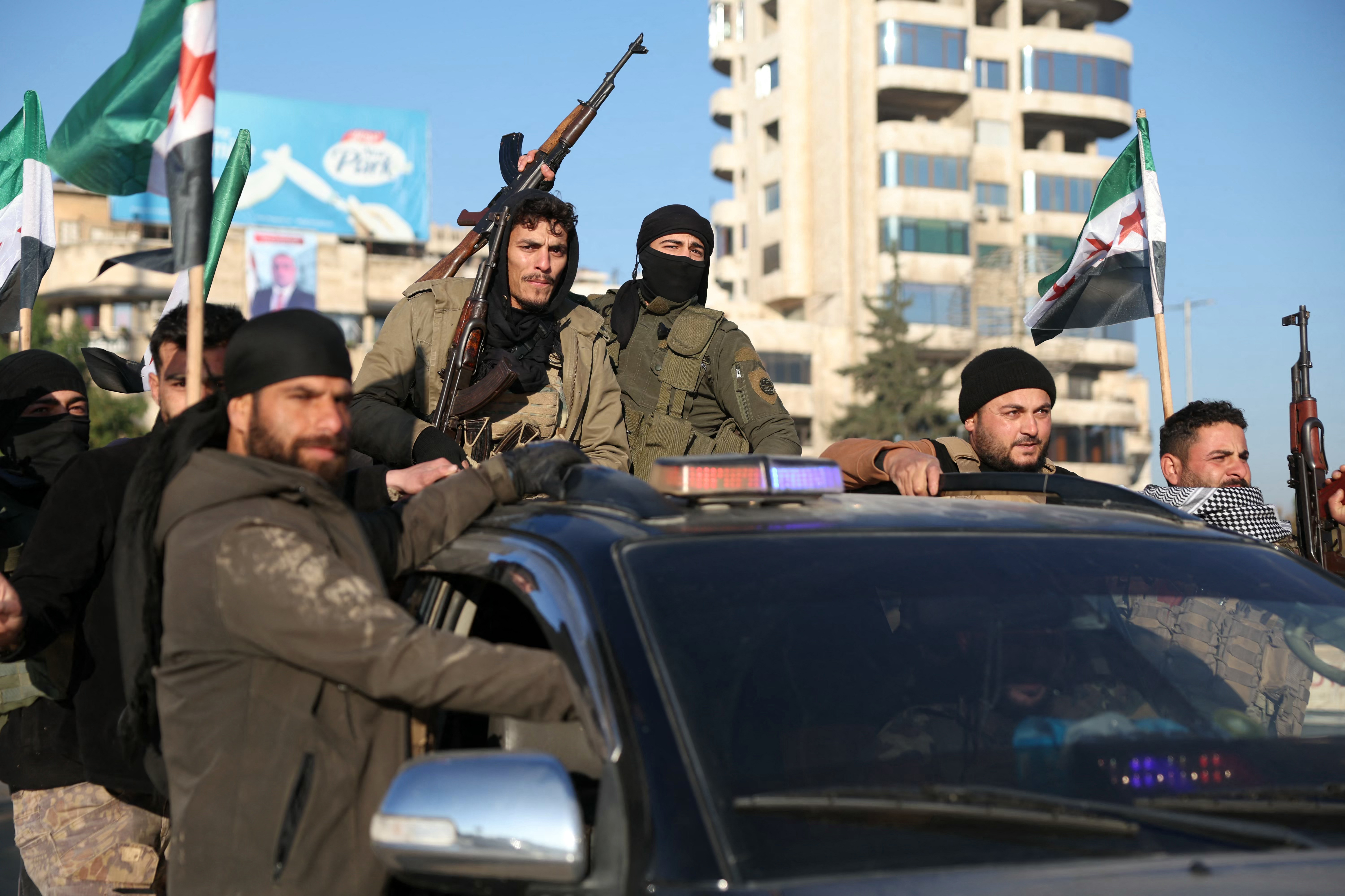 Anti-government fighters brandish their guns as they ride a vehicle in Syria's northern city of Aleppo last week. Photo / AFP