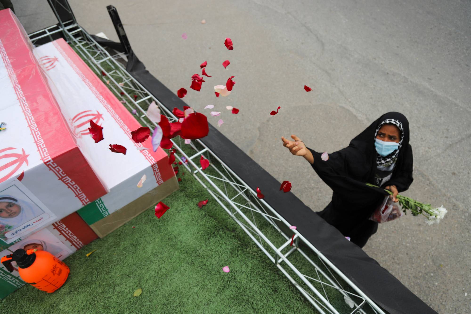 A mourner sprays flower petals on the coffins of children who were killed in a reported strike on a primary school in Iran's Hormozgan province. Photo / Amirhossein Khorgooei, ISNA, AFP