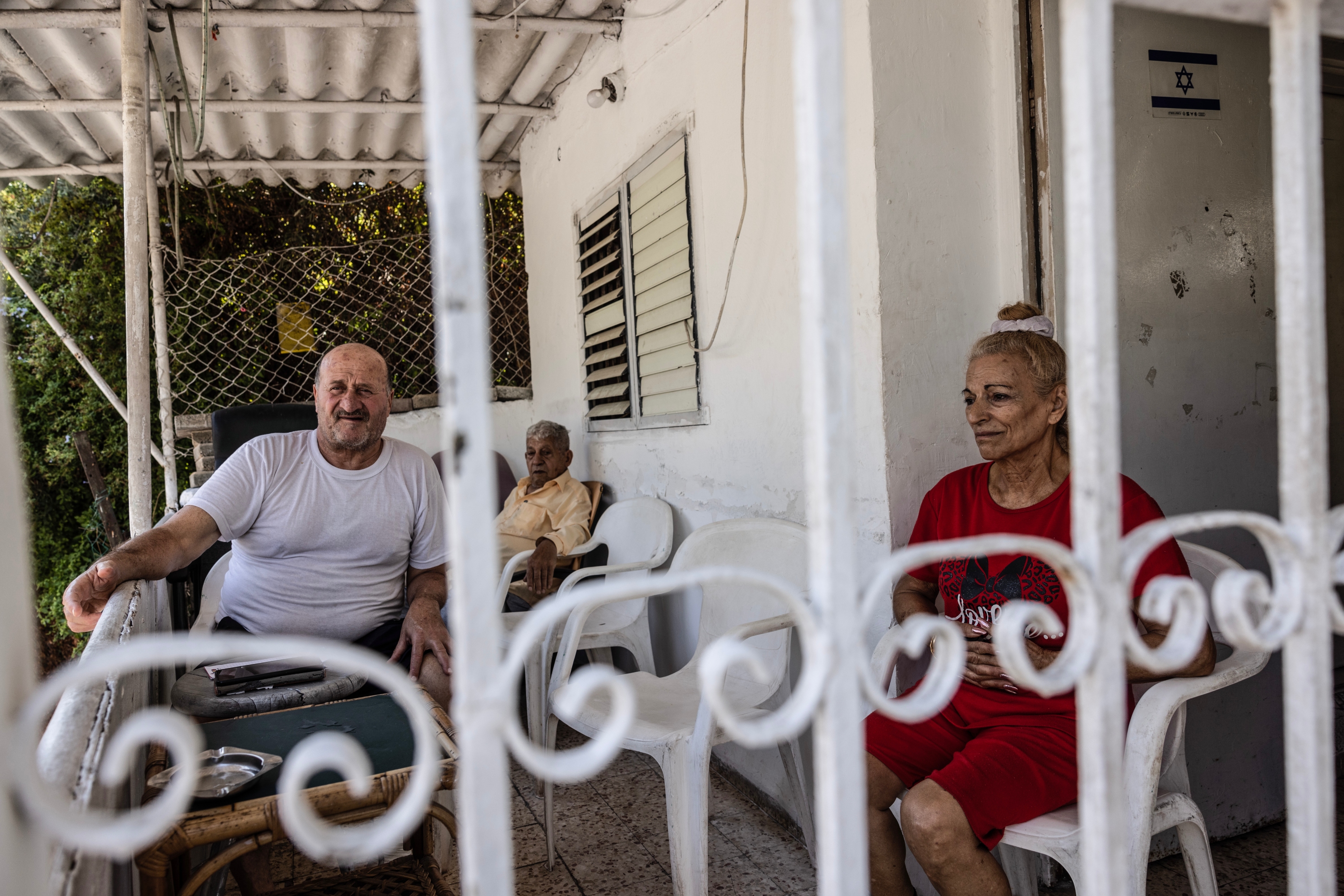 Miriam Hadad, 60, sits with her neighbours Bashira Bahdadt, 68, left, and Edmund Muklashi, 78, on the porch of her home in Haifa on Sunday. Photo / Heidi Levine for The Washington Post