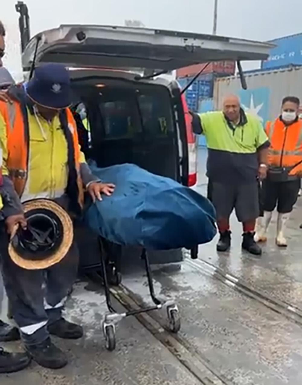 Port workers pay their respects as Atiroa Tuaiti's body is prepared for transport after an accident at the Ports of Auckland on Tuesday. Photo / Supplied
