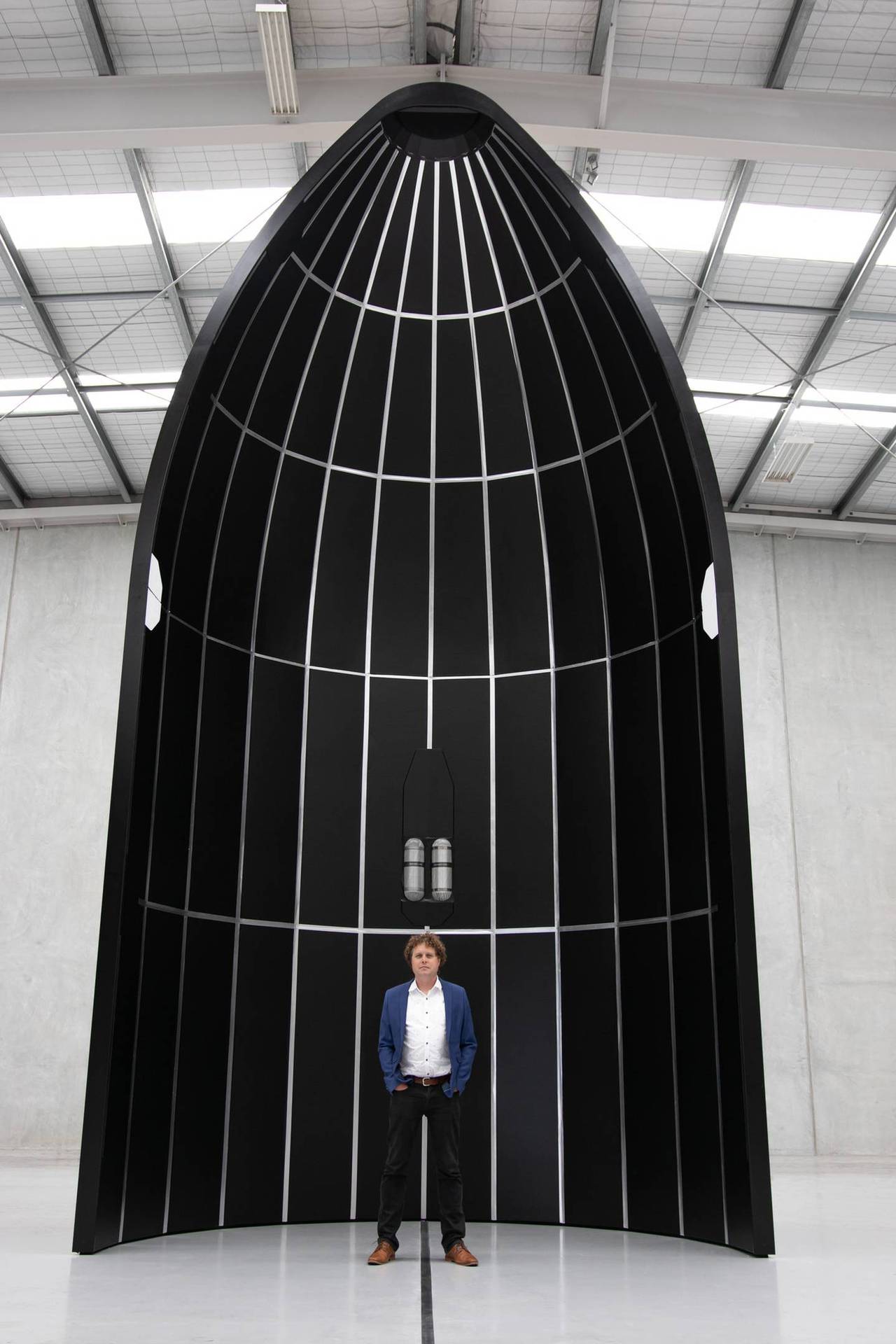 Rocket Lab founder and CEO Peter Beck with a mockup of the nose cone for his company's larger new, crew-capable Neutron Rocket, due to be launched in 2024. Photo / File

