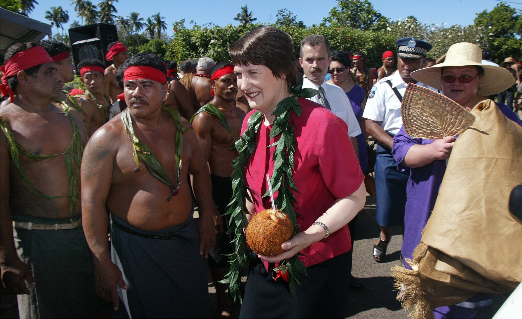 Prime Minister Helen Clark and Kiwi Tamasese walk past Samoan men dressed as Mau protesters after laying a wreath on the grave of Tupua Tamasese Lealofi lll in Apia in 2002. Photo / Herald file