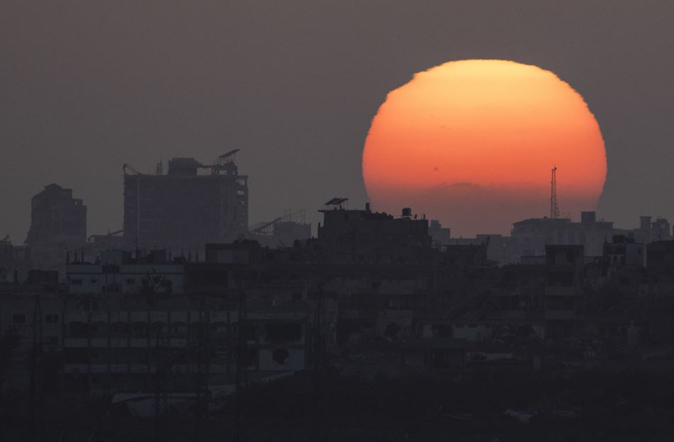 The sun sets behind the buildings in the Gaza Strip as seen from southern Israel. Photo / AP