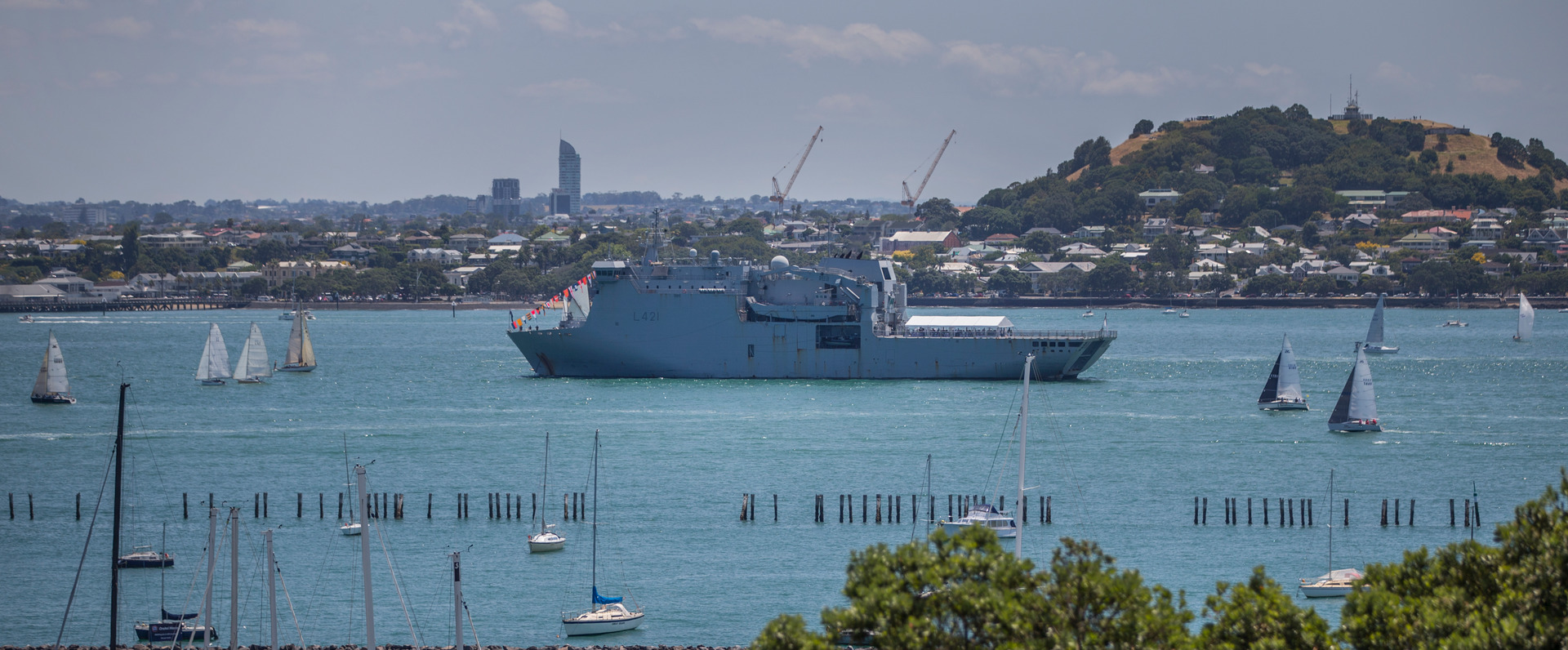Yachts pass by the HMNZS Canterbury as it makes its way up the Waitemata Harbour.