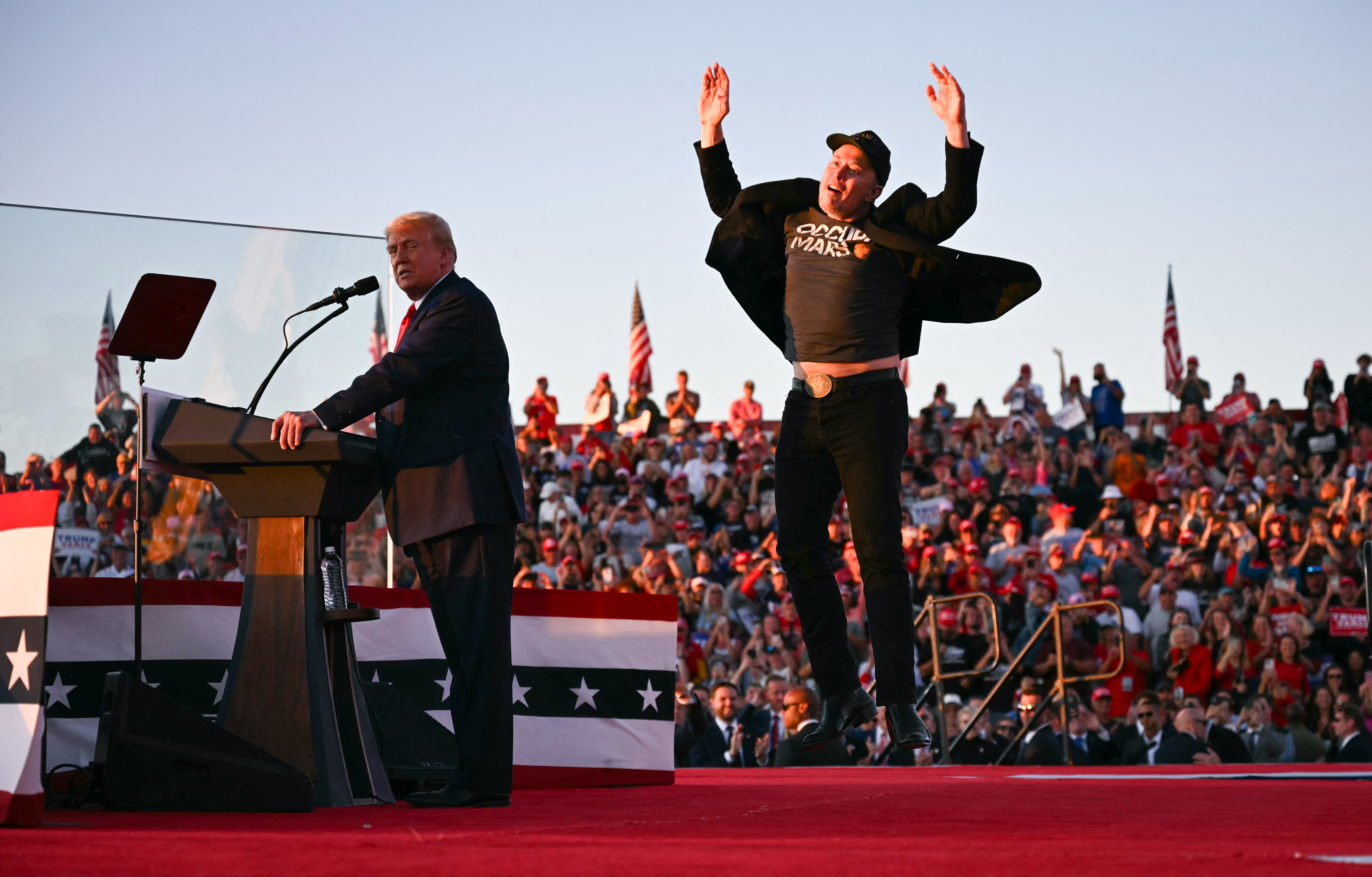 Tesla CEO Elon Musk (right) jumps on stage as he joins Donald Trump (left) during a campaign rally at site of his first assassination attempt in Butler, Pennsylvania. Photo / AFP