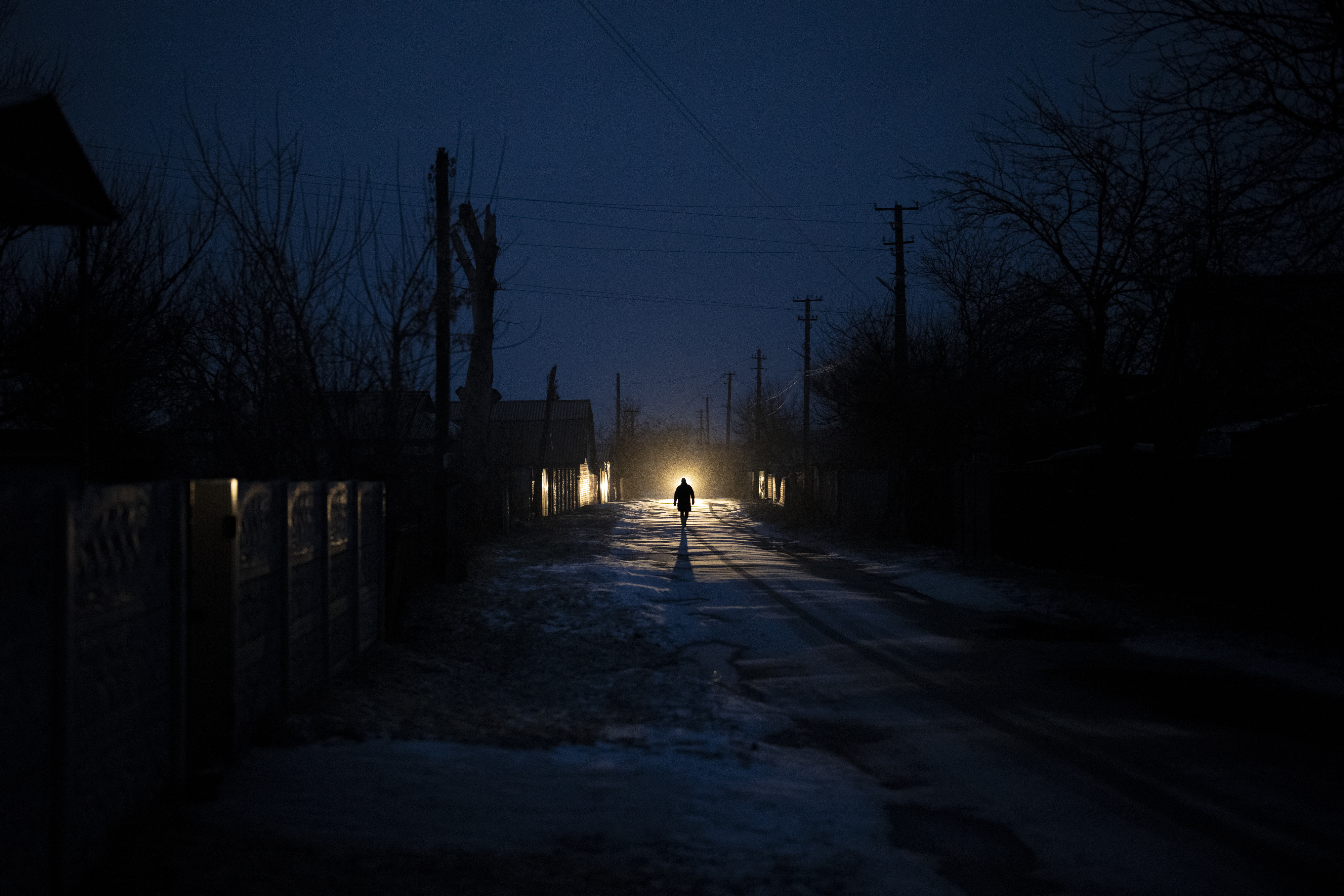 A man is silhouetted in the headlights of a car during a blackout in the town of Kolychivka, Ukraine. Photo / AP