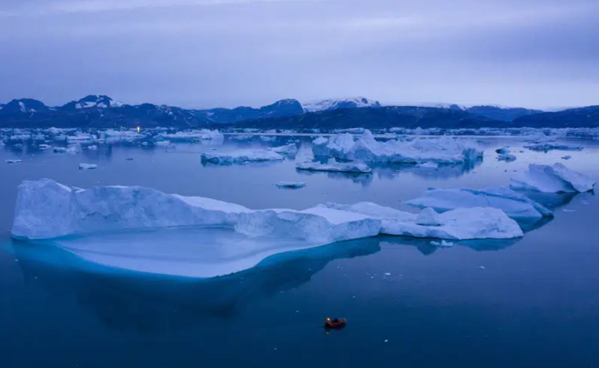 A boat navigates at night next to large icebergs near the town of Kulusuk, in eastern Greenland. Photo / AP